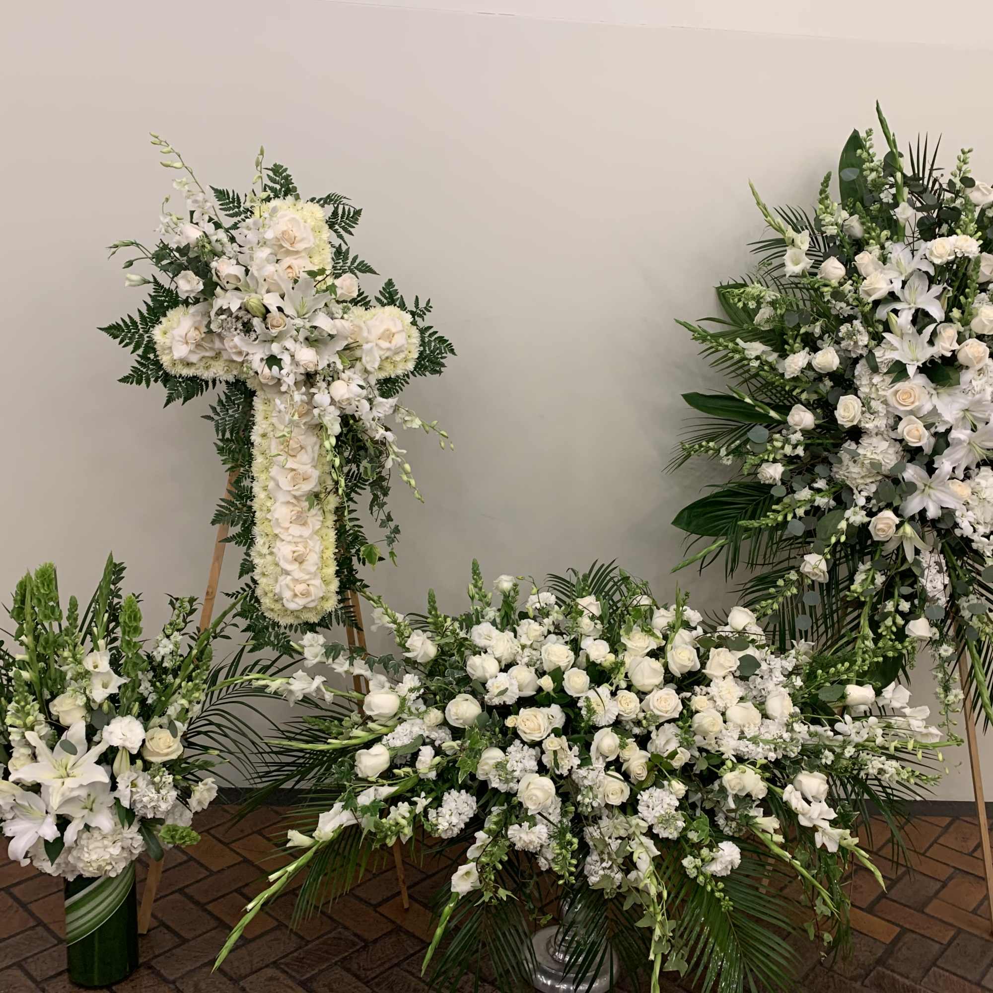 Four white floral funeral arrangements with lilies and roses