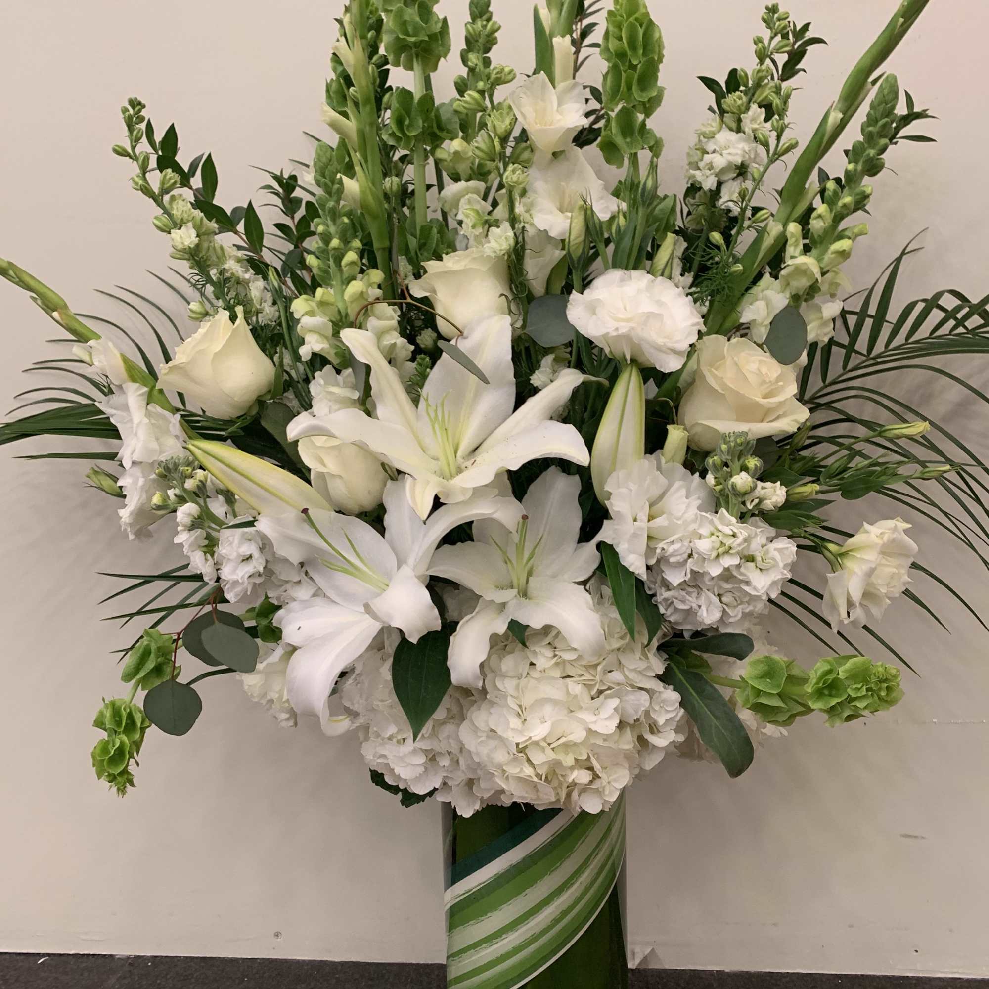White lilies and roses in a tall green vase