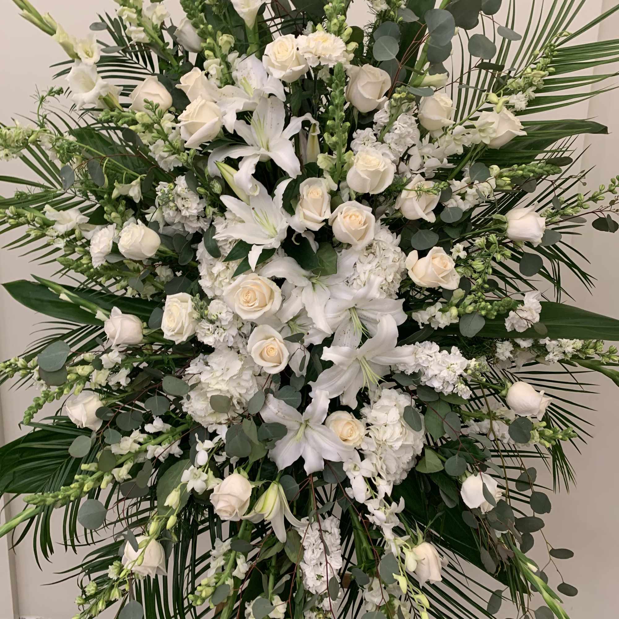 Large white floral standing spray with roses and lilies