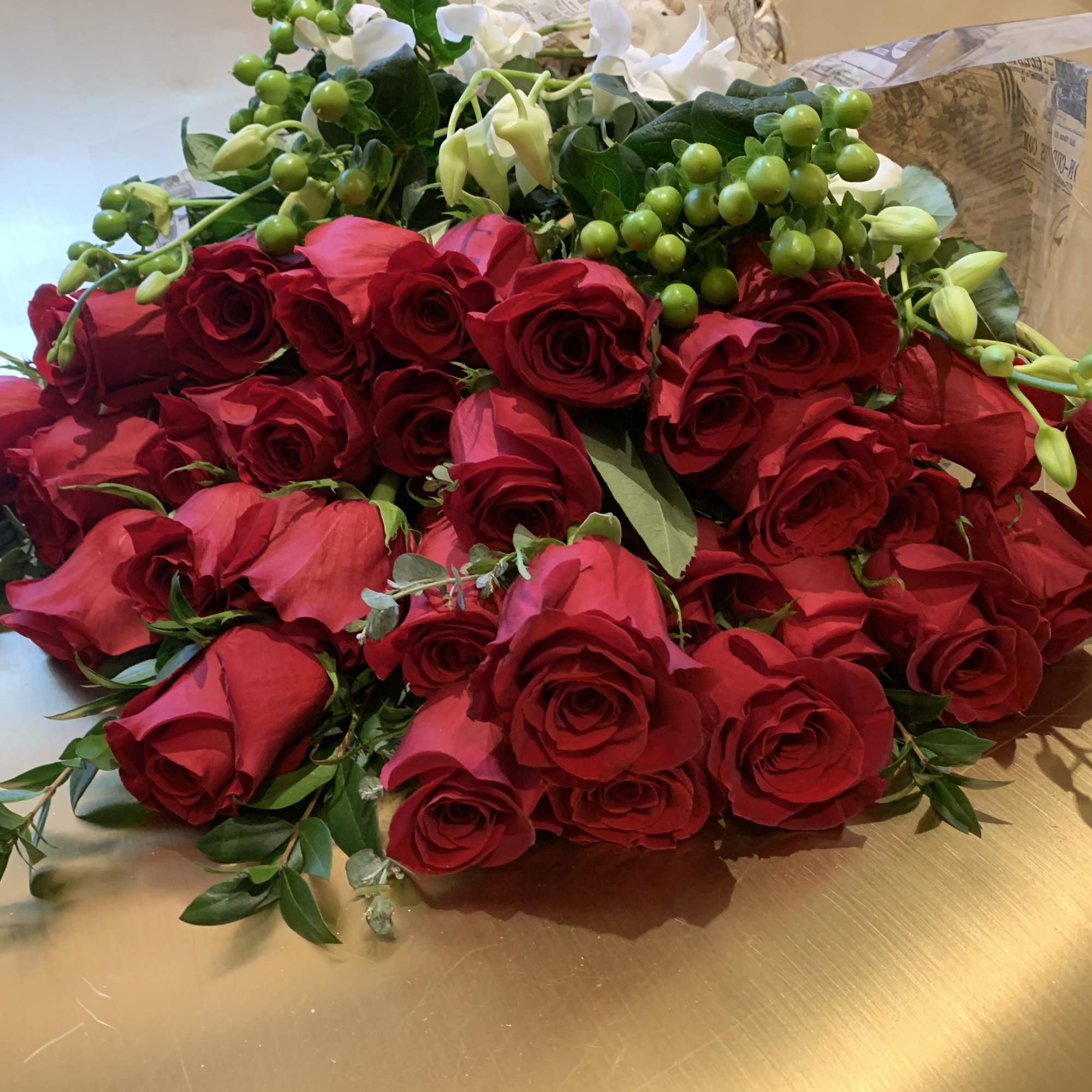 Bouquet of red roses with green berries and white blooms