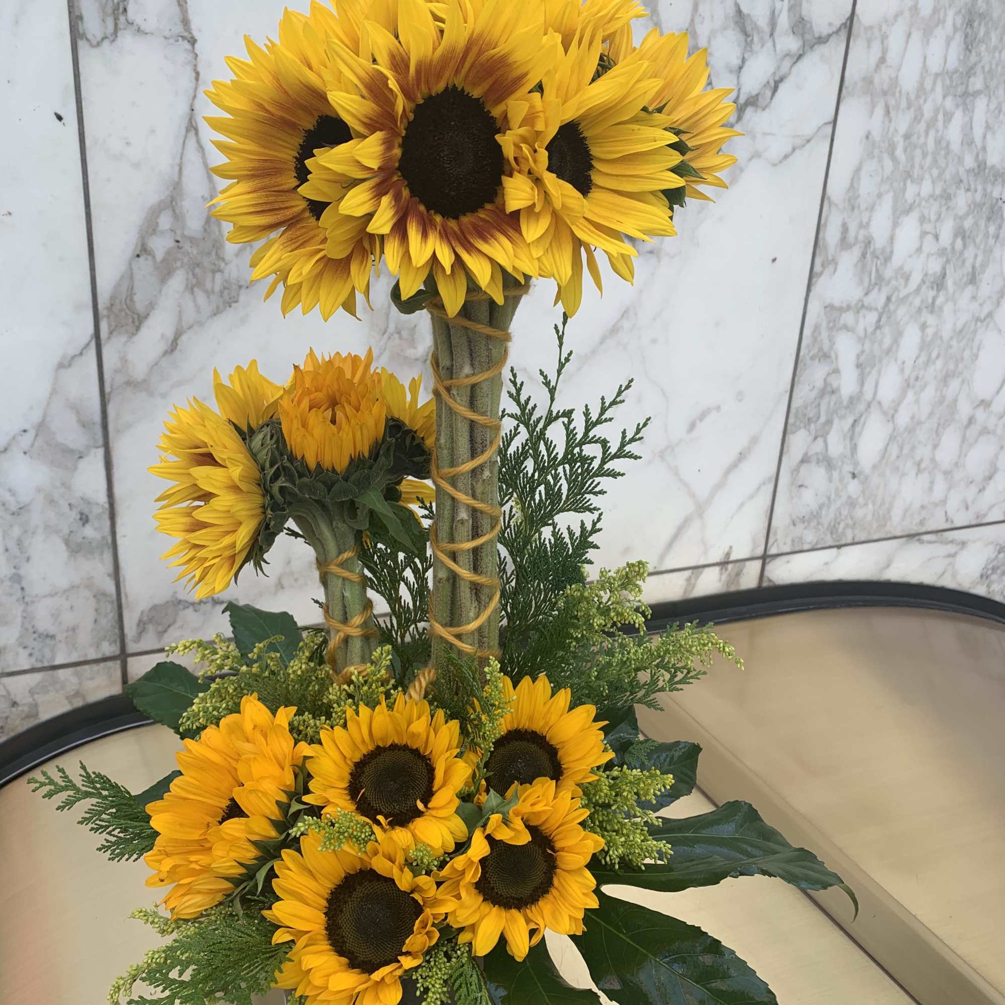 Sunflower arrangement in a white container with two tall stems and a lower cluster