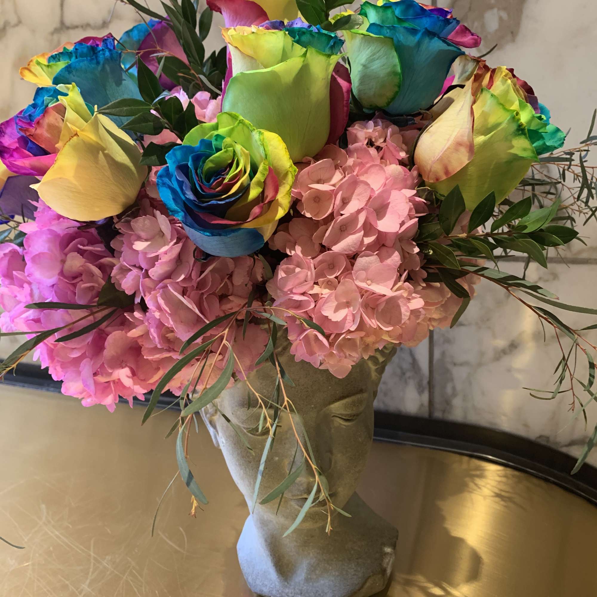 Rainbow roses and pink hydrangeas in a sculpted vase