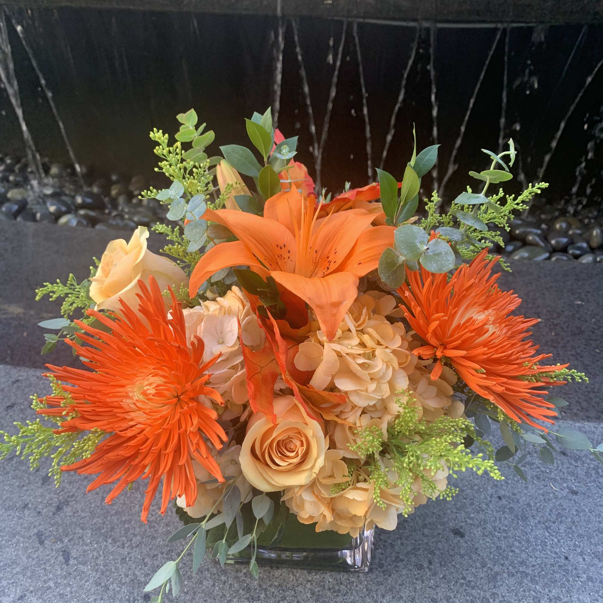 Orange bouquet with lilies, roses, and chrysanthemums in a glass vase