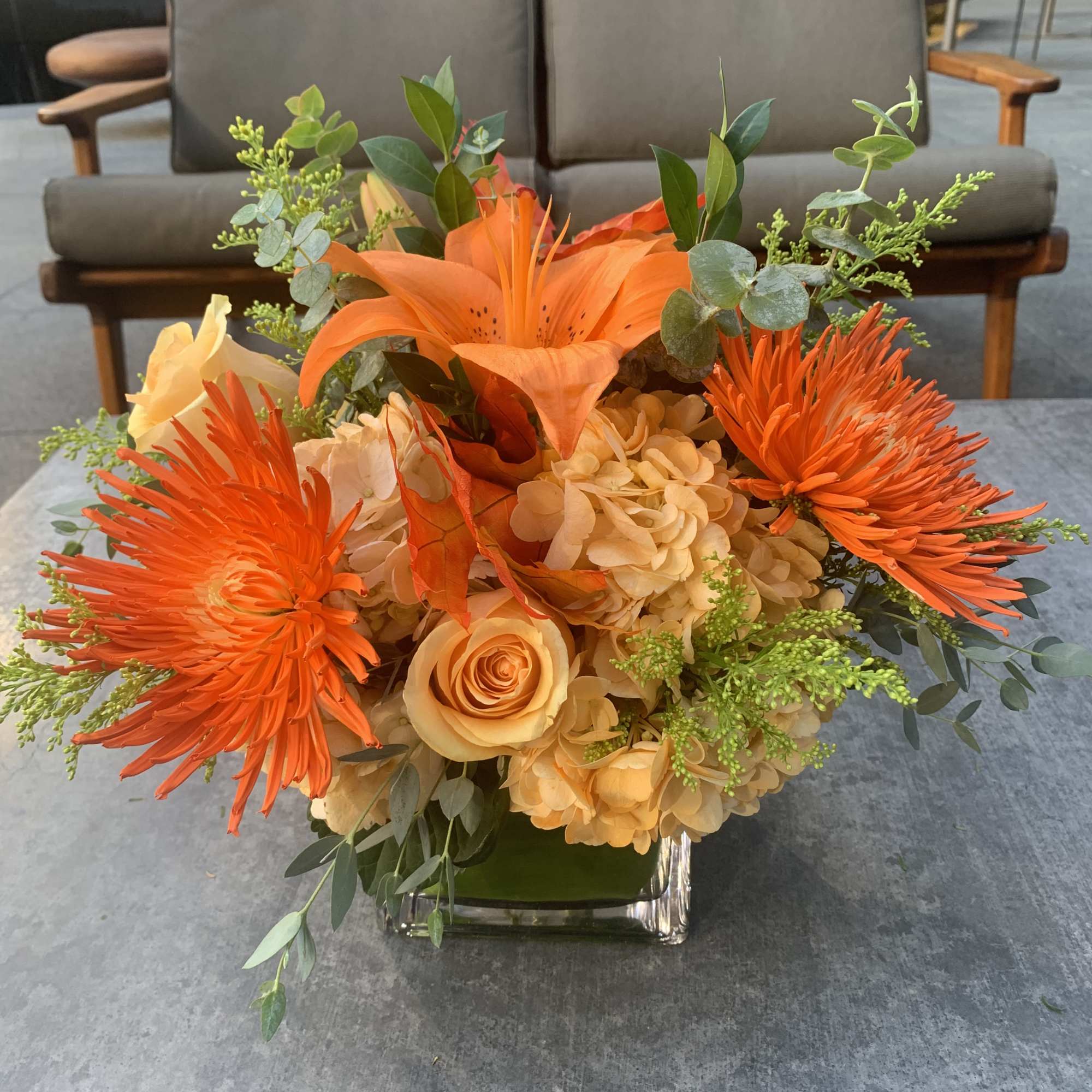 Orange and peach floral arrangement in a glass vase