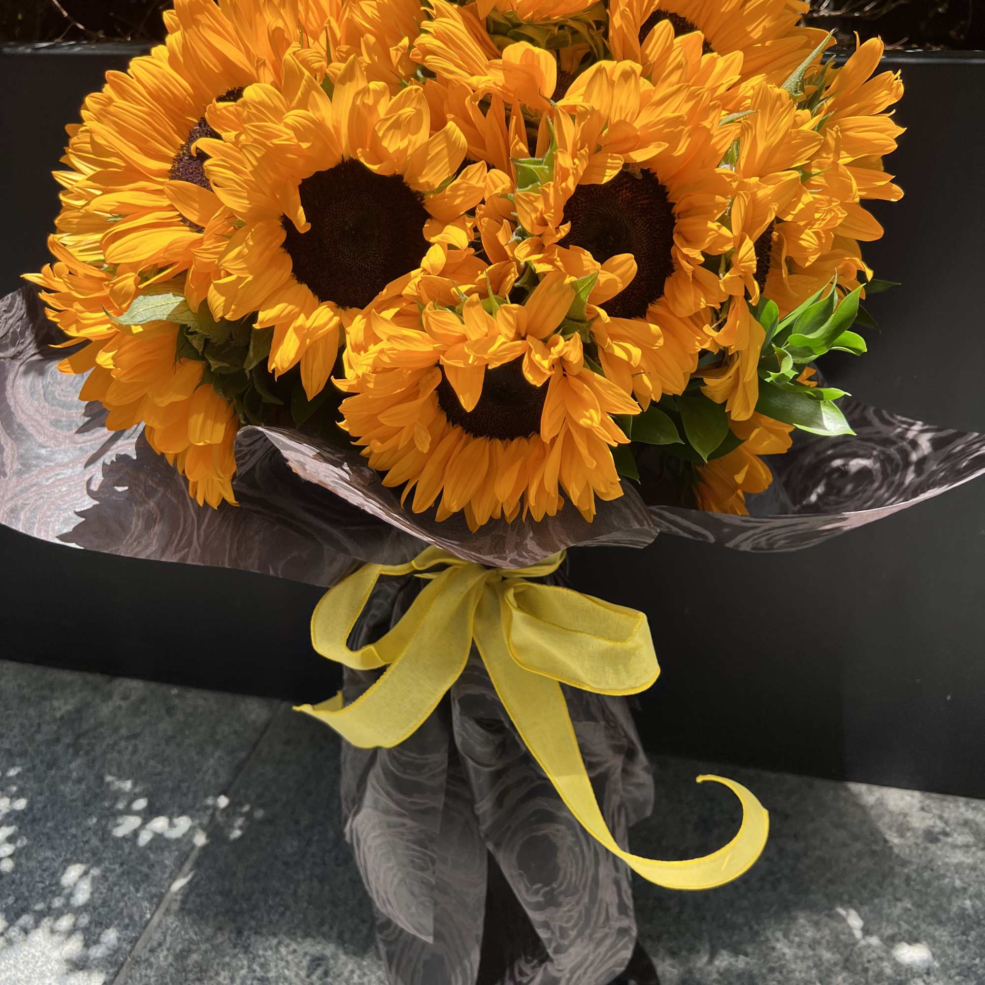 Bouquet of bright yellow sunflowers wrapped with a yellow ribbon