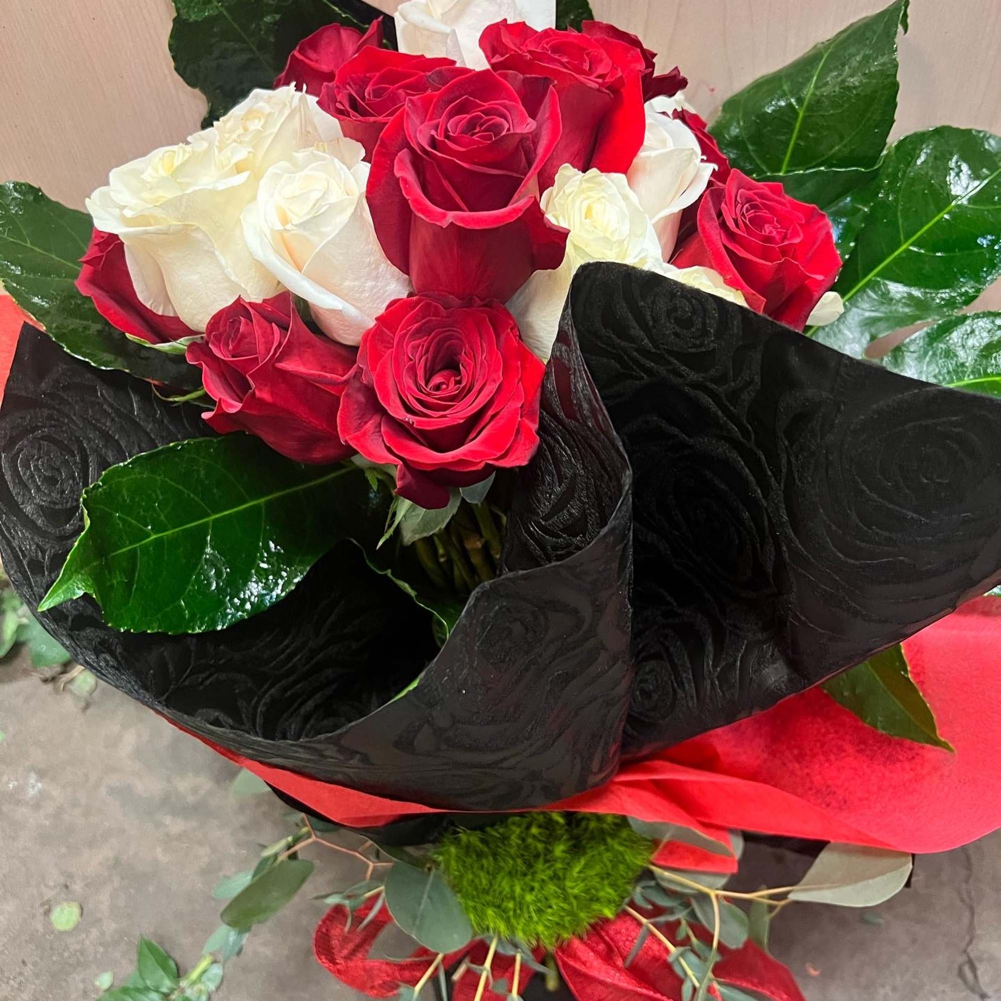 Bouquet of red and white roses wrapped in black paper