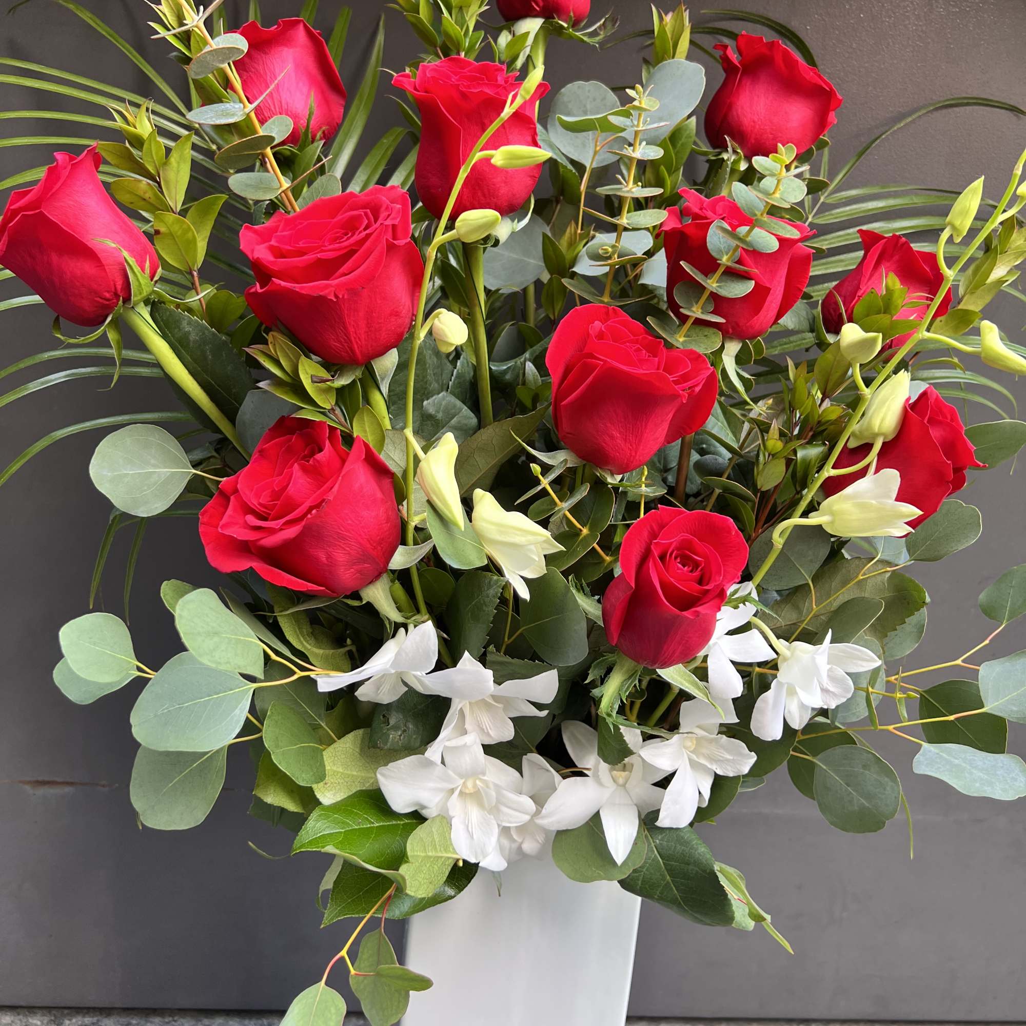 Tall bouquet of red roses and white flowers in a white vase
