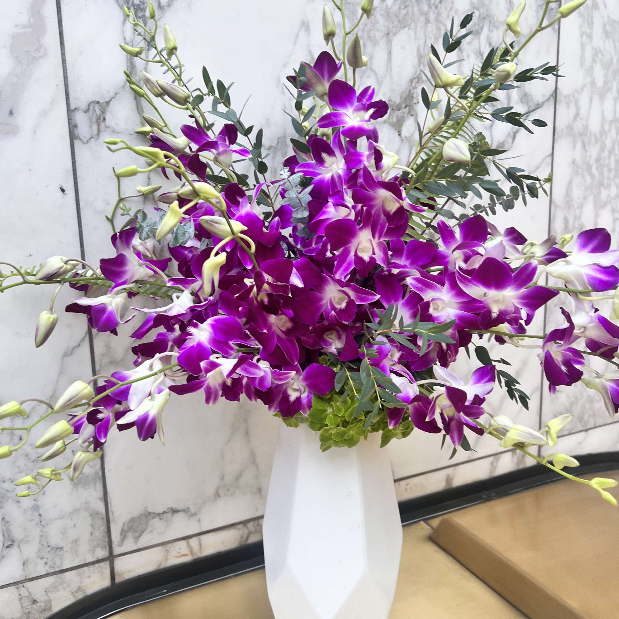 Purple orchids arranged in a white vase