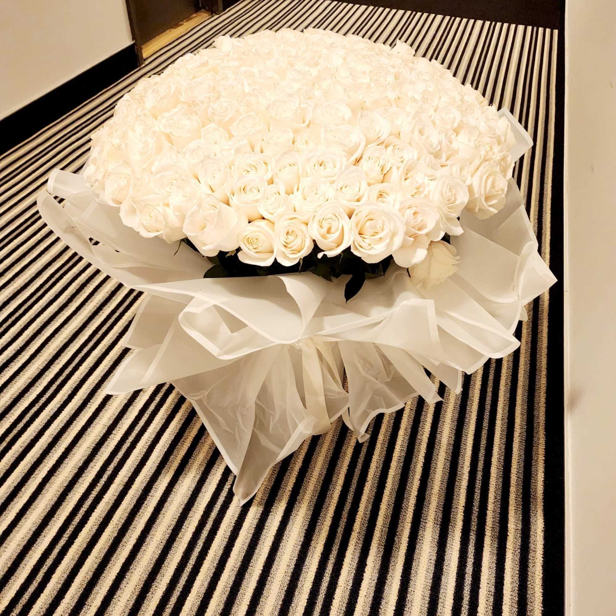 Large bouquet of white roses wrapped in sheer white fabric