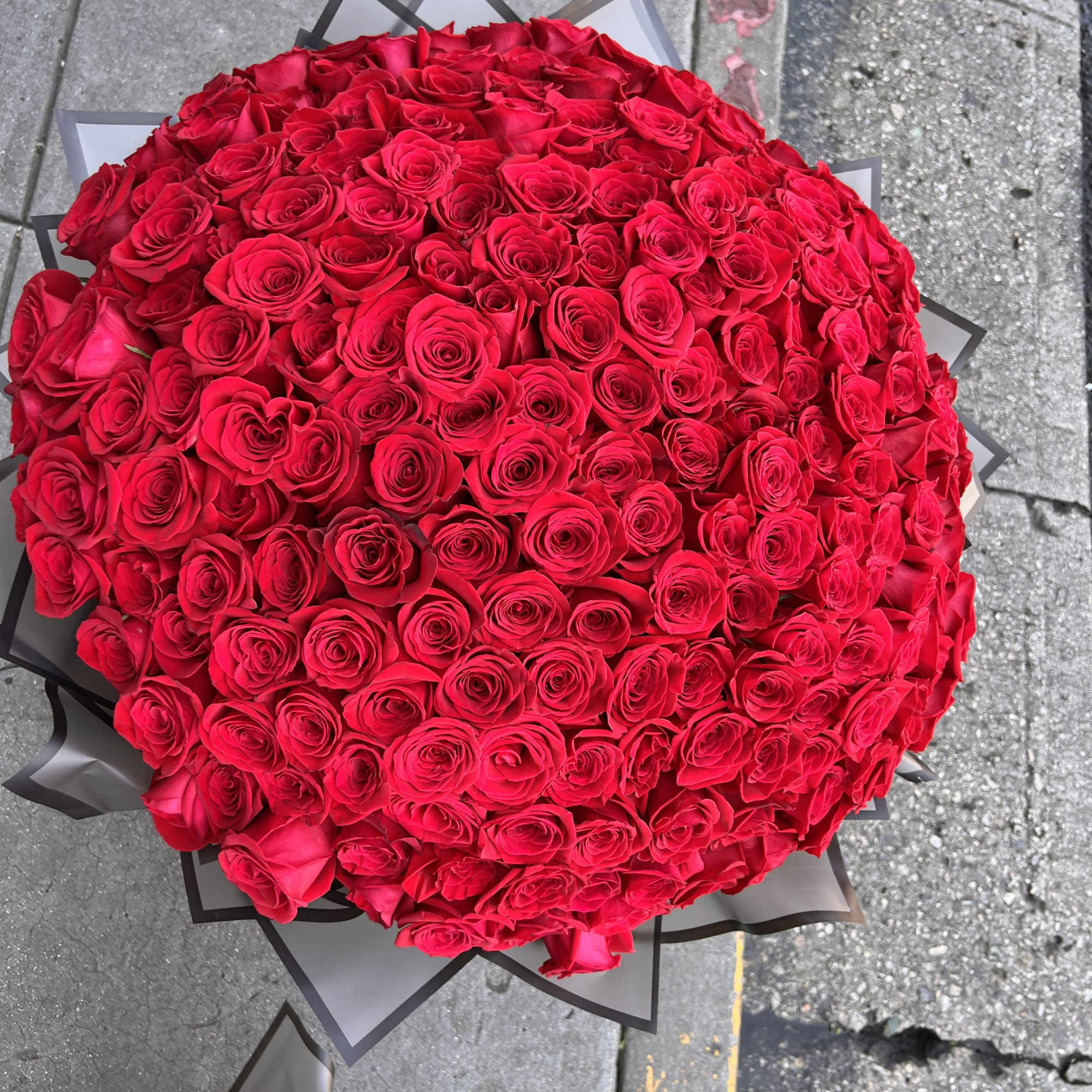 Large round bouquet of red roses wrapped in black paper
