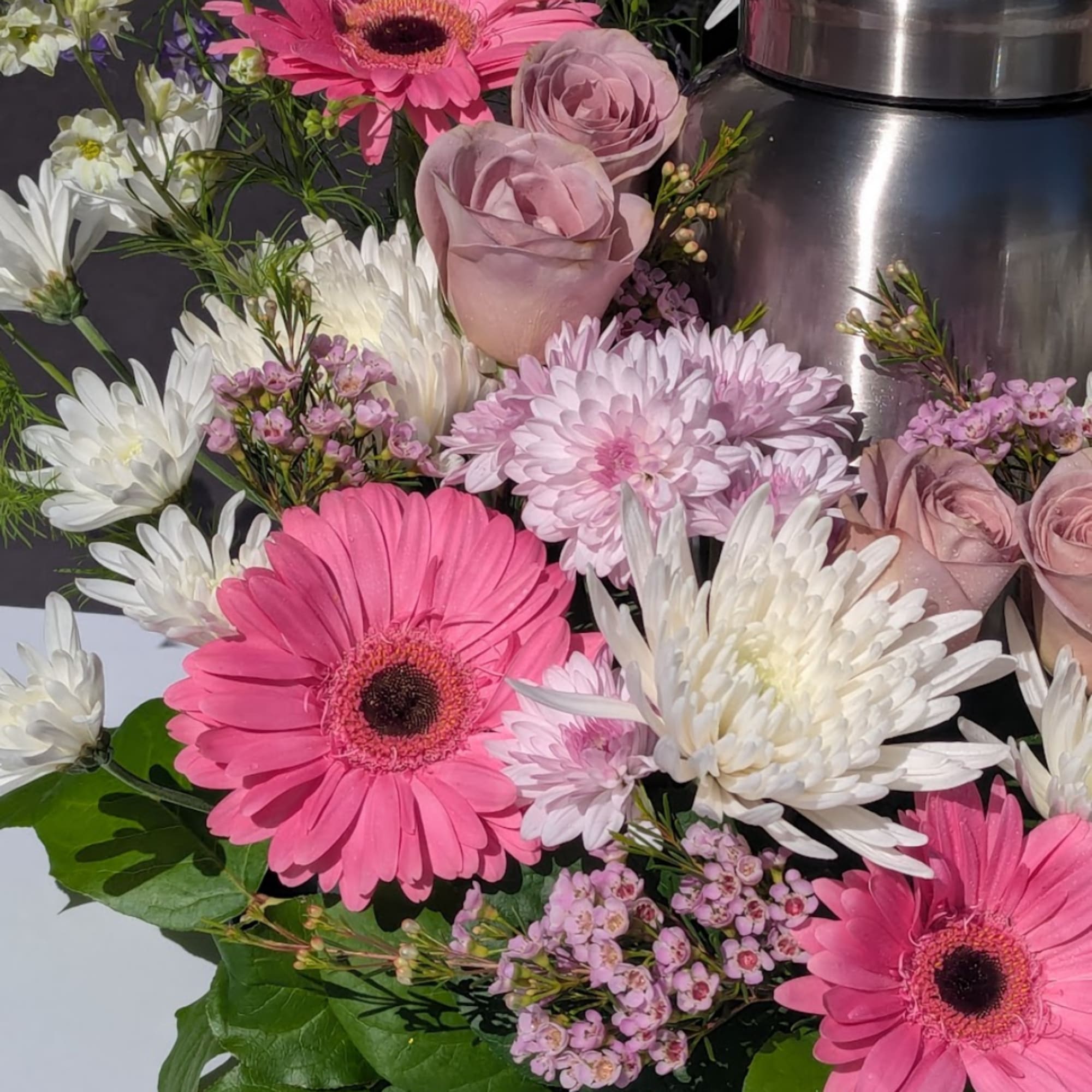 Pink gerbera daisies, pale roses, and white chrysanthemums arranged together