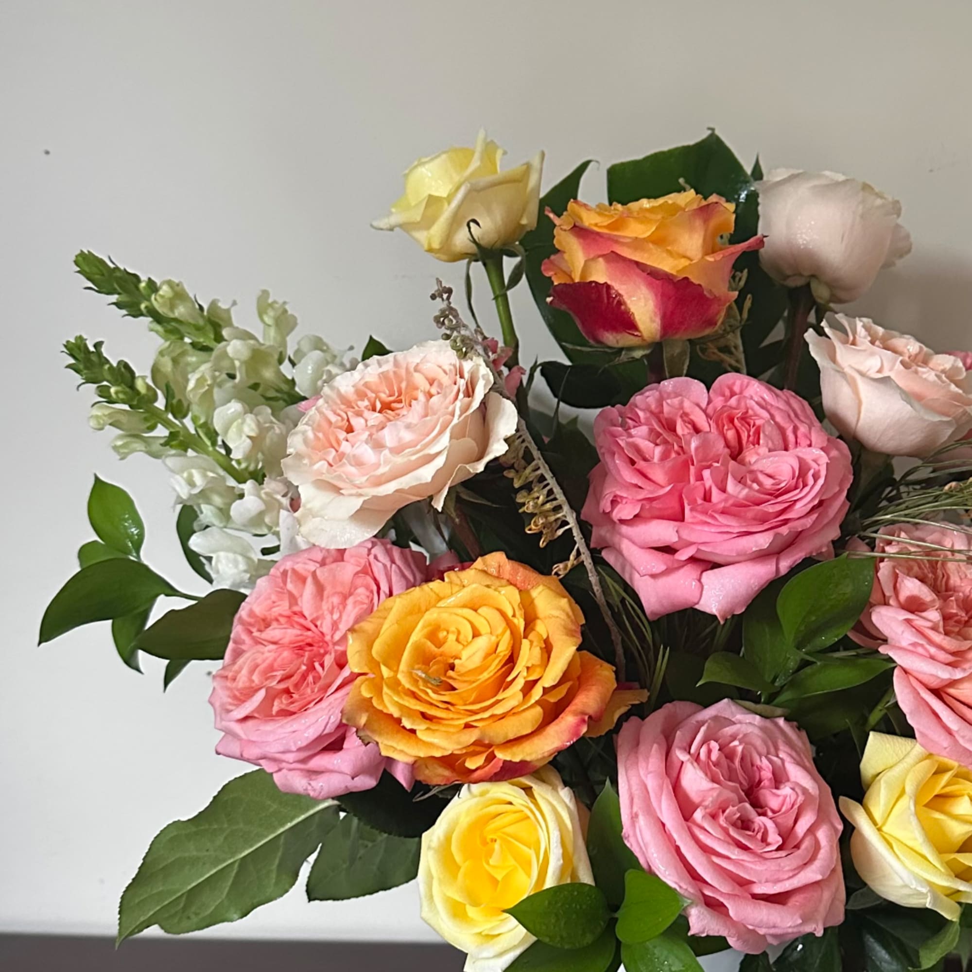 Bouquet of multicolored roses with white snapdragons and greenery
