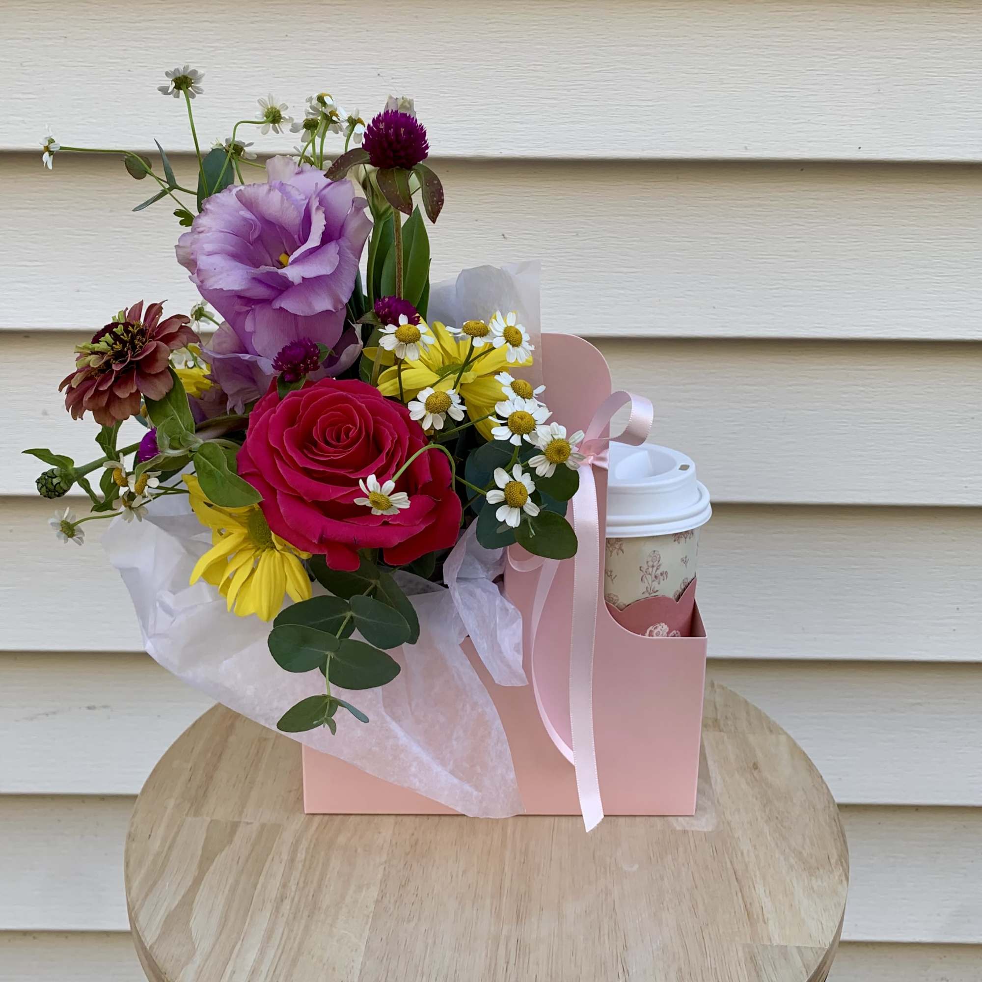 Mixed bouquet with a pink rose, purple lisianthus, and daisies in a pink gift bag