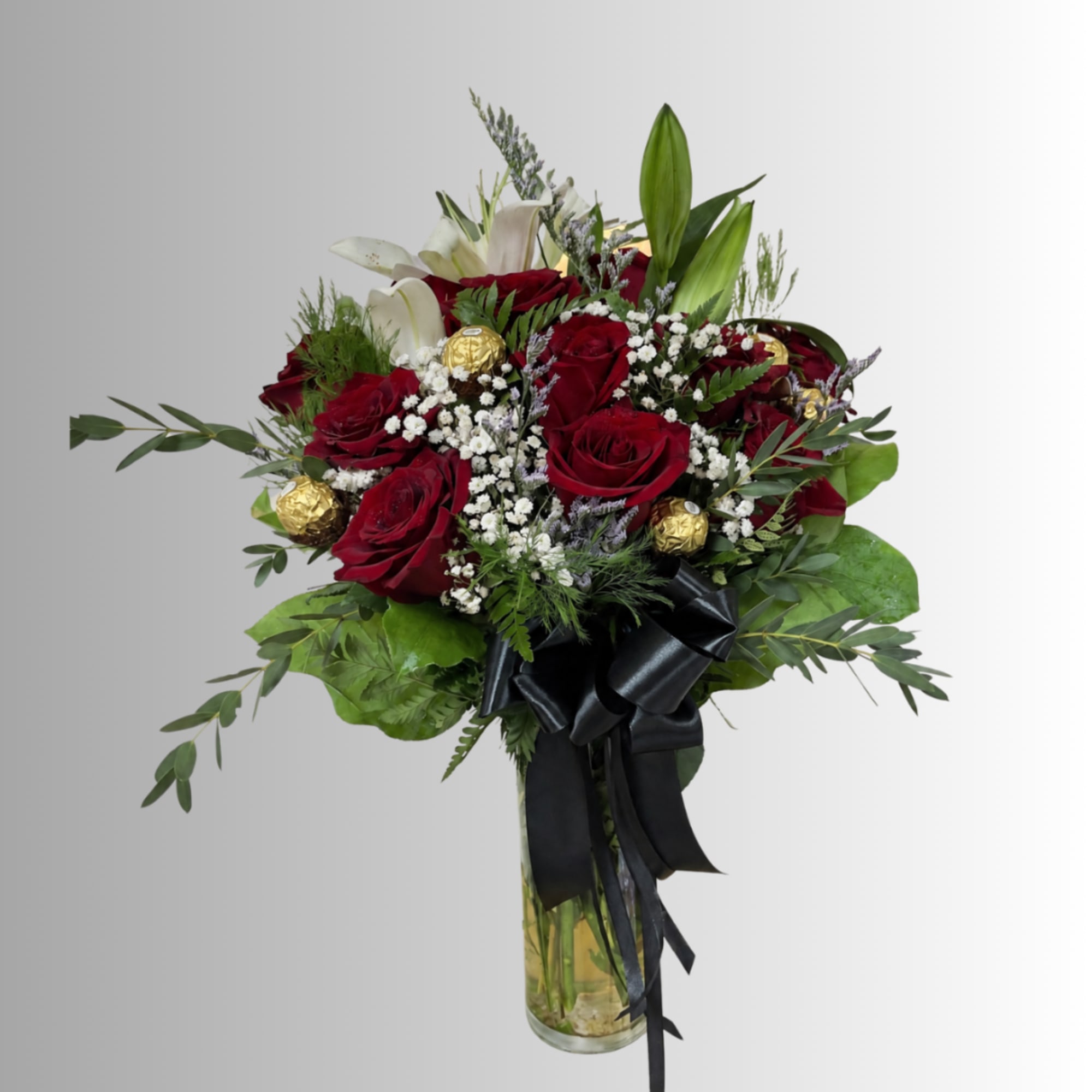 Red roses and white lilies in a glass vase with a black ribbon