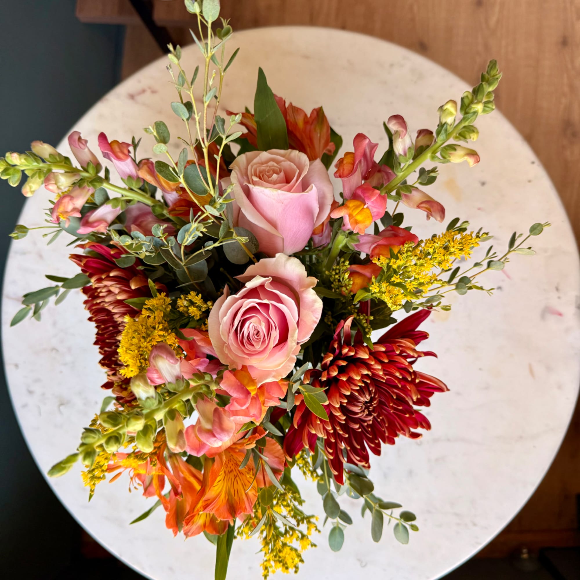 Pink roses with orange and red mixed flowers in a bouquet