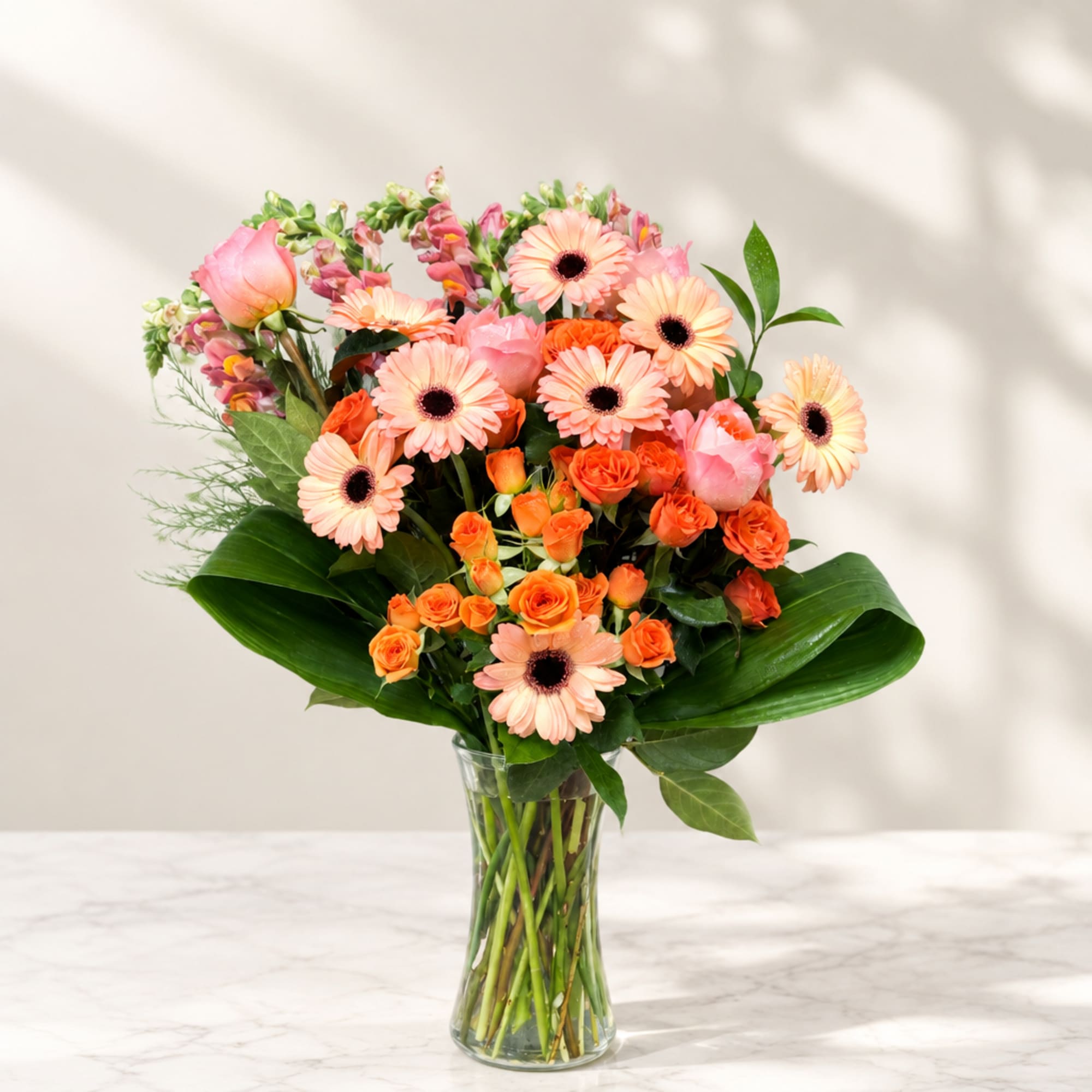 Pink and orange mixed bouquet in a clear glass vase
