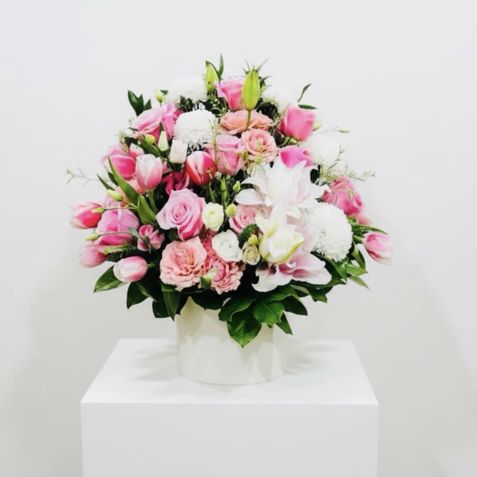 Soft blush pink roses and tulips mingle with creamy white lilies in