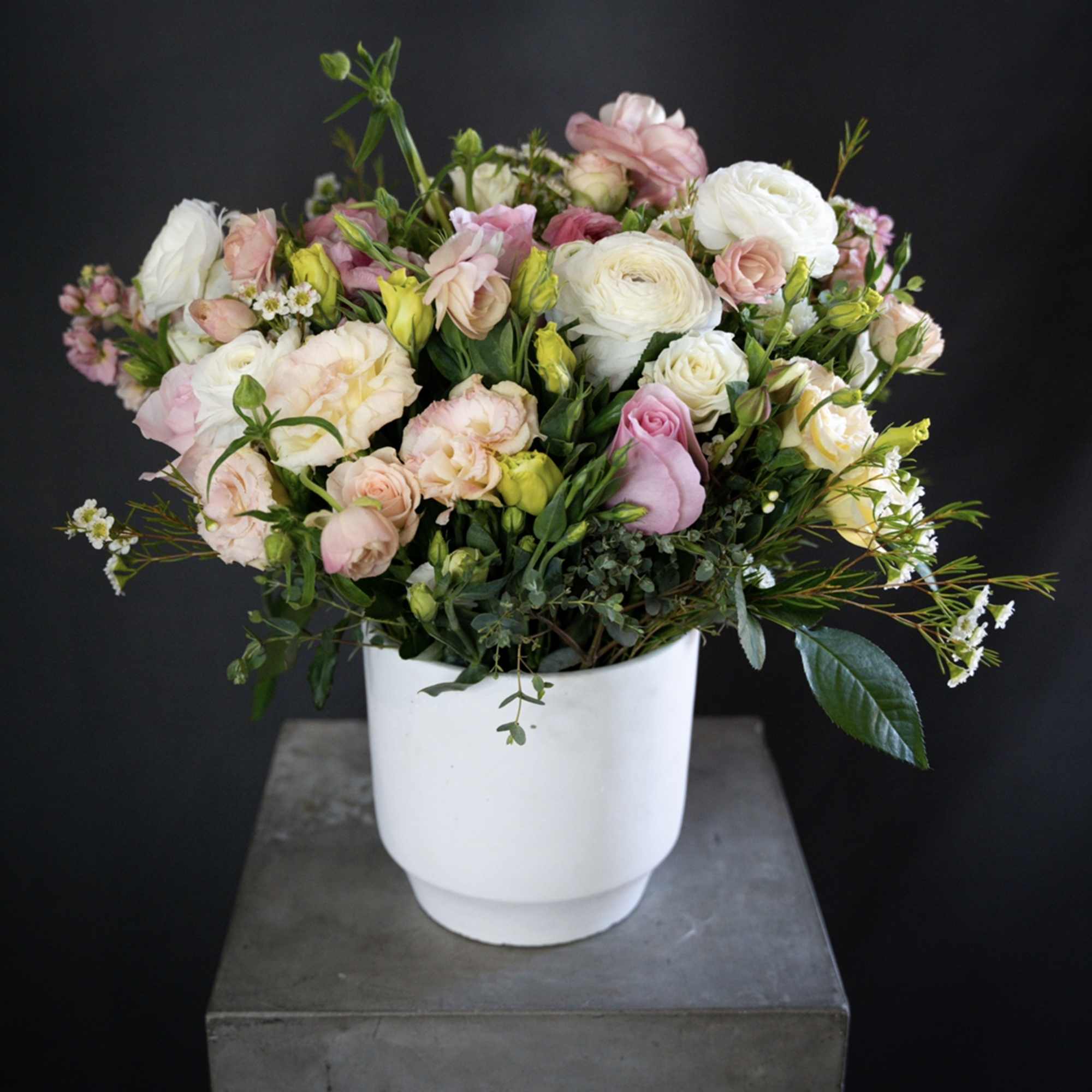Pastel bouquet of roses and ranunculus in a white vase