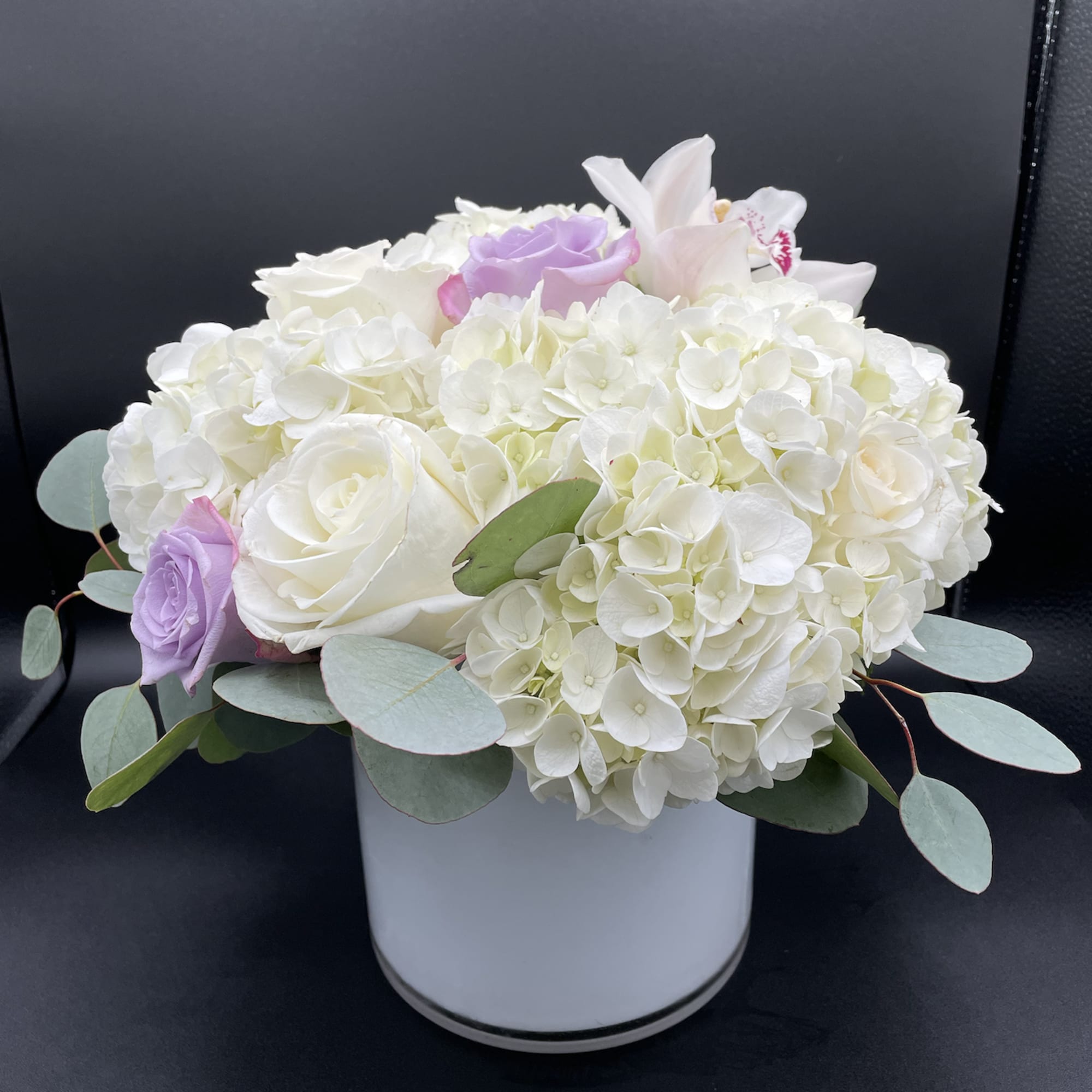 White hydrangea and roses in a white vase with pale purple accents