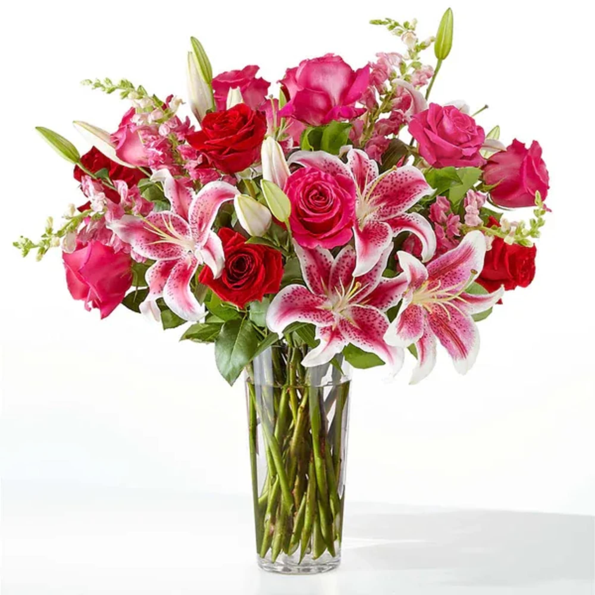 Bouquet of pink and red roses with pink lilies in a clear glass vase