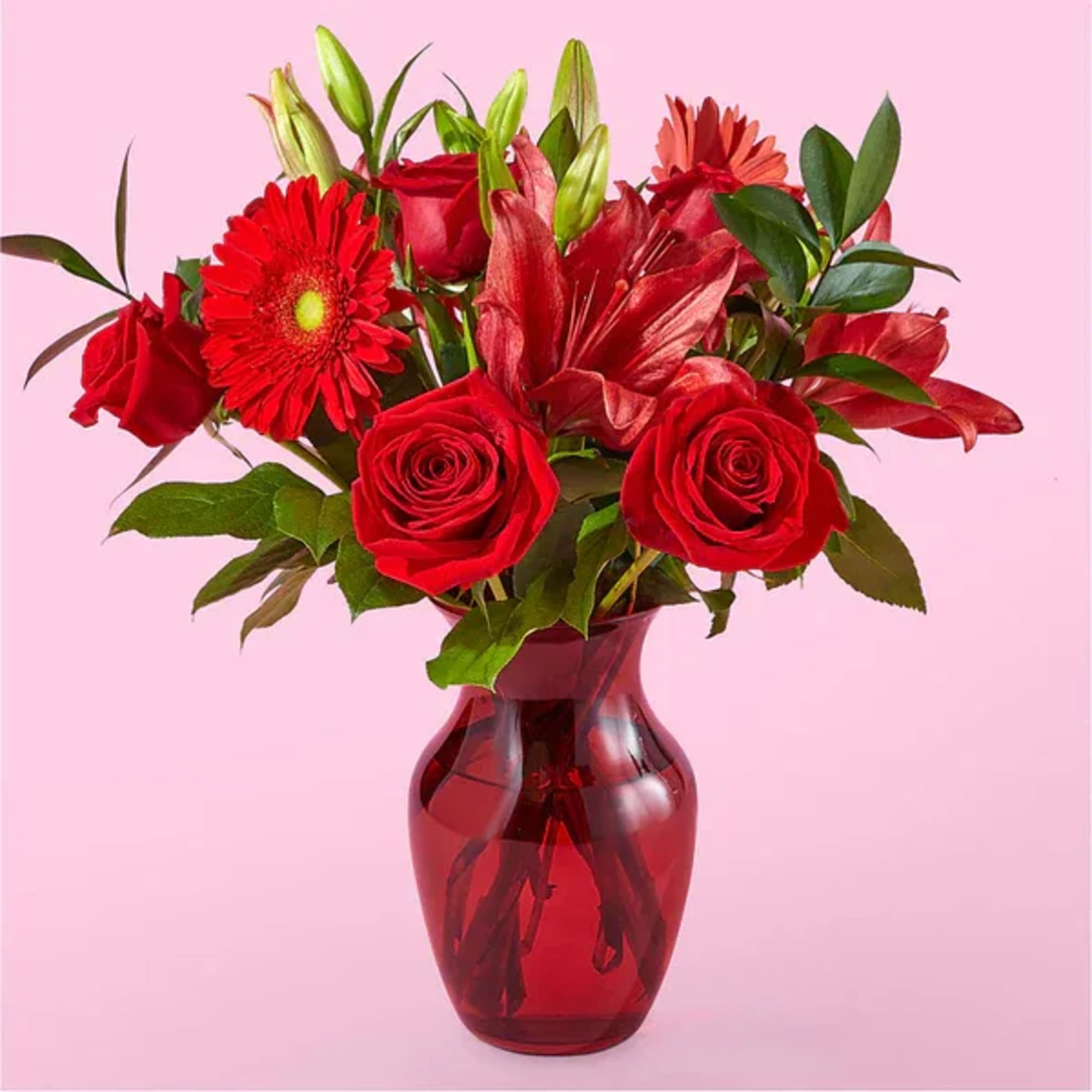 Red roses and lilies in a red glass vase