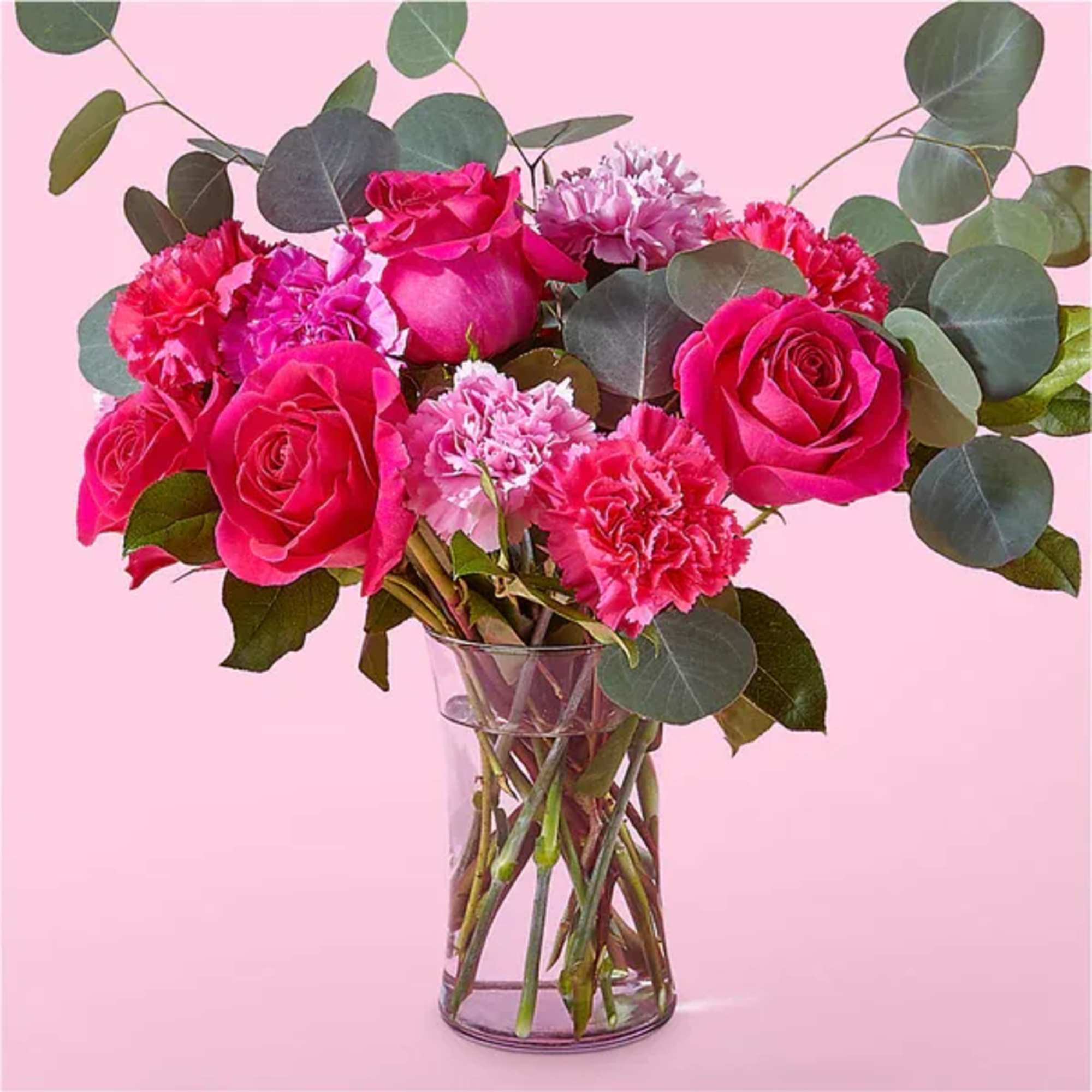 Pink roses and carnations in a clear glass vase