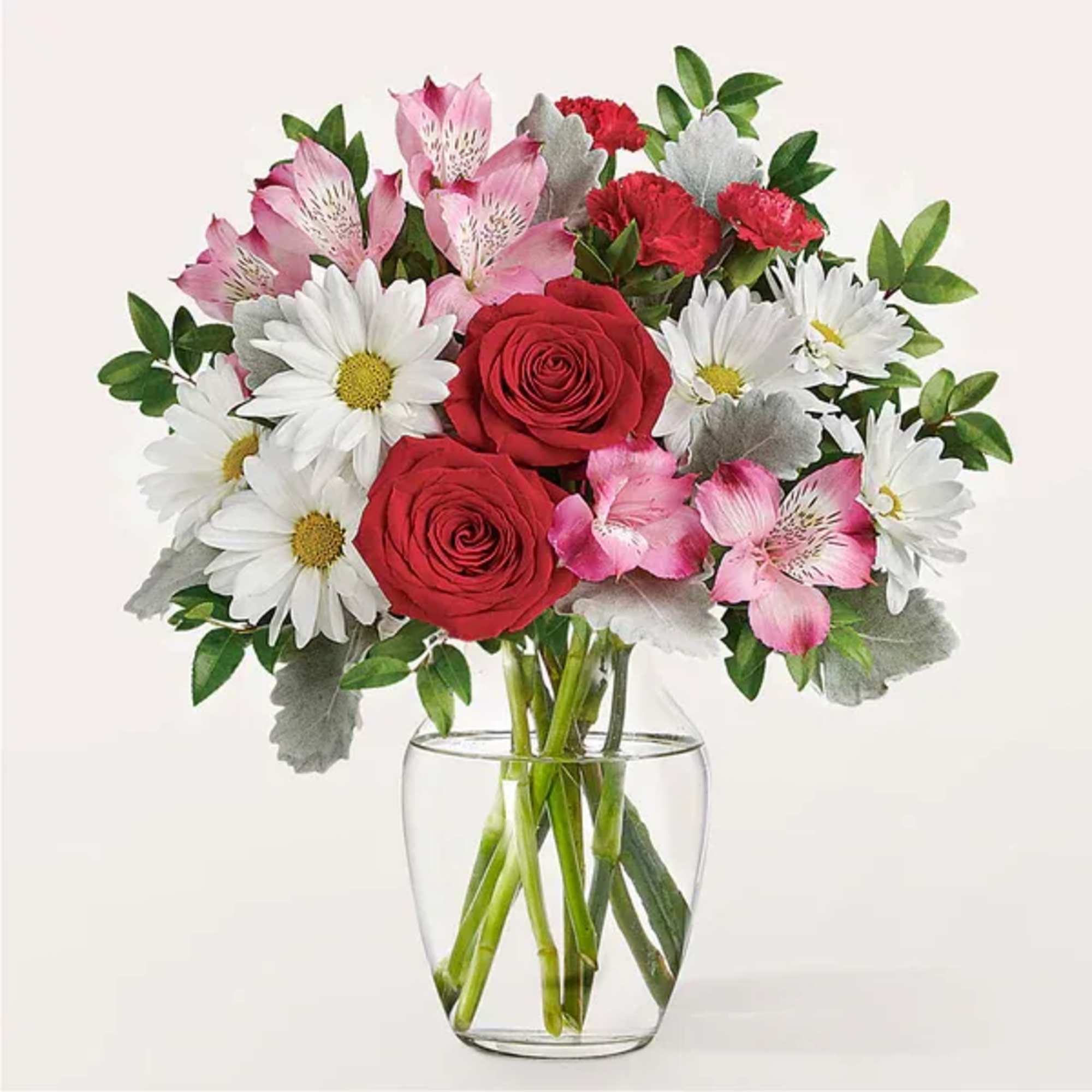 Bouquet of red roses, white daisies, and pink alstroemeria in a clear glass vase