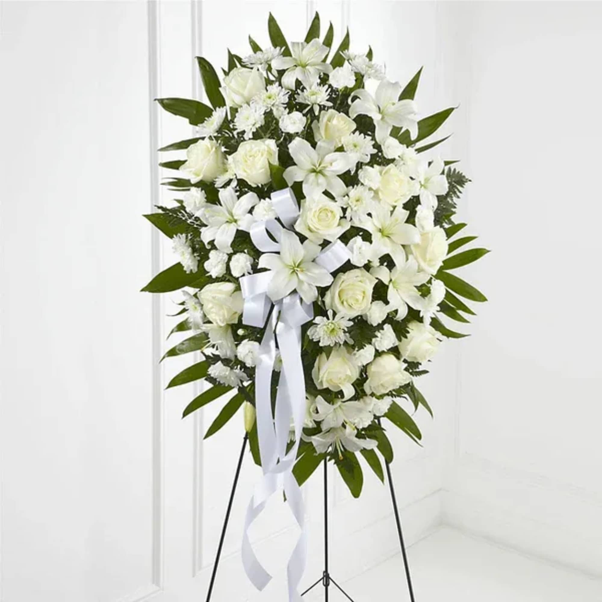 White floral standing spray on a black easel with a white ribbon