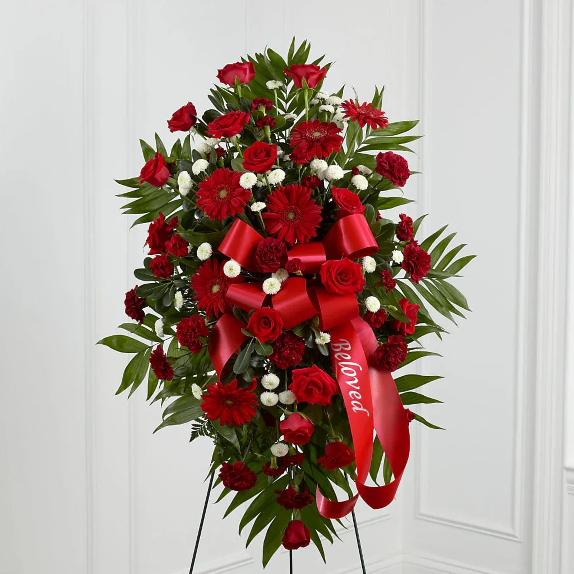 Standing spray of red roses and gerbera daisies with a red ribbon