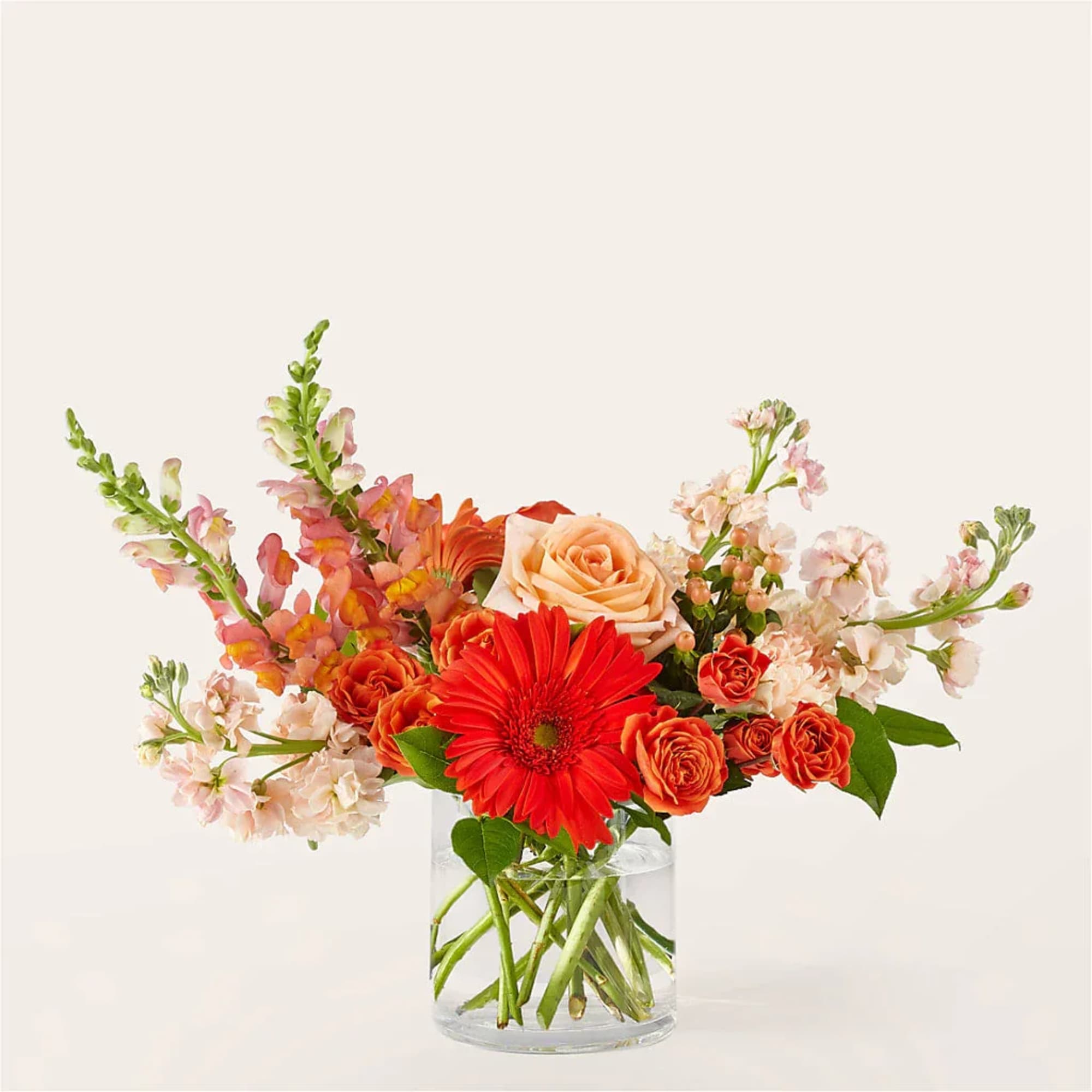 Mixed bouquet of orange and pink flowers in a clear glass vase