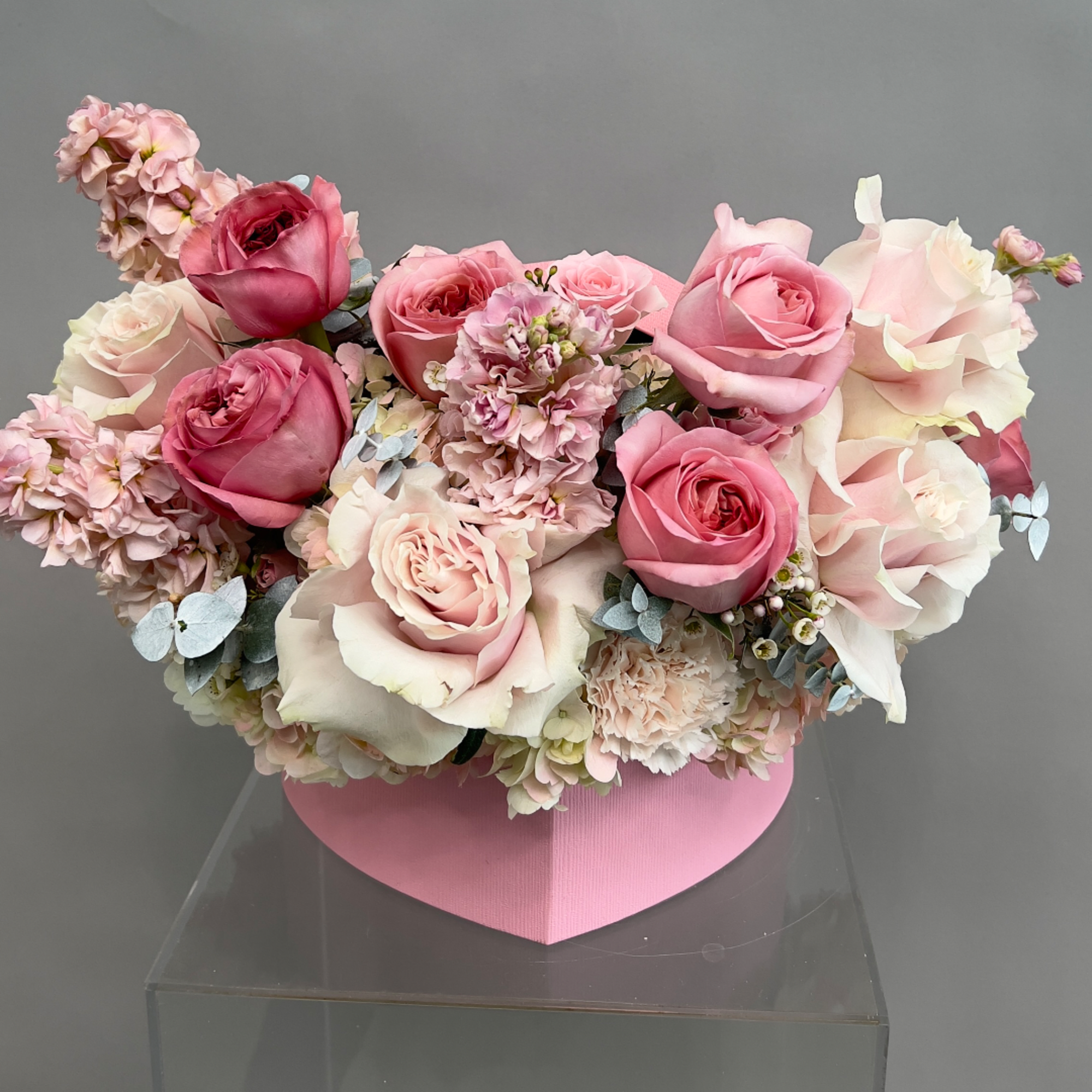 Pink and white rose arrangement in a pink heart-shaped box