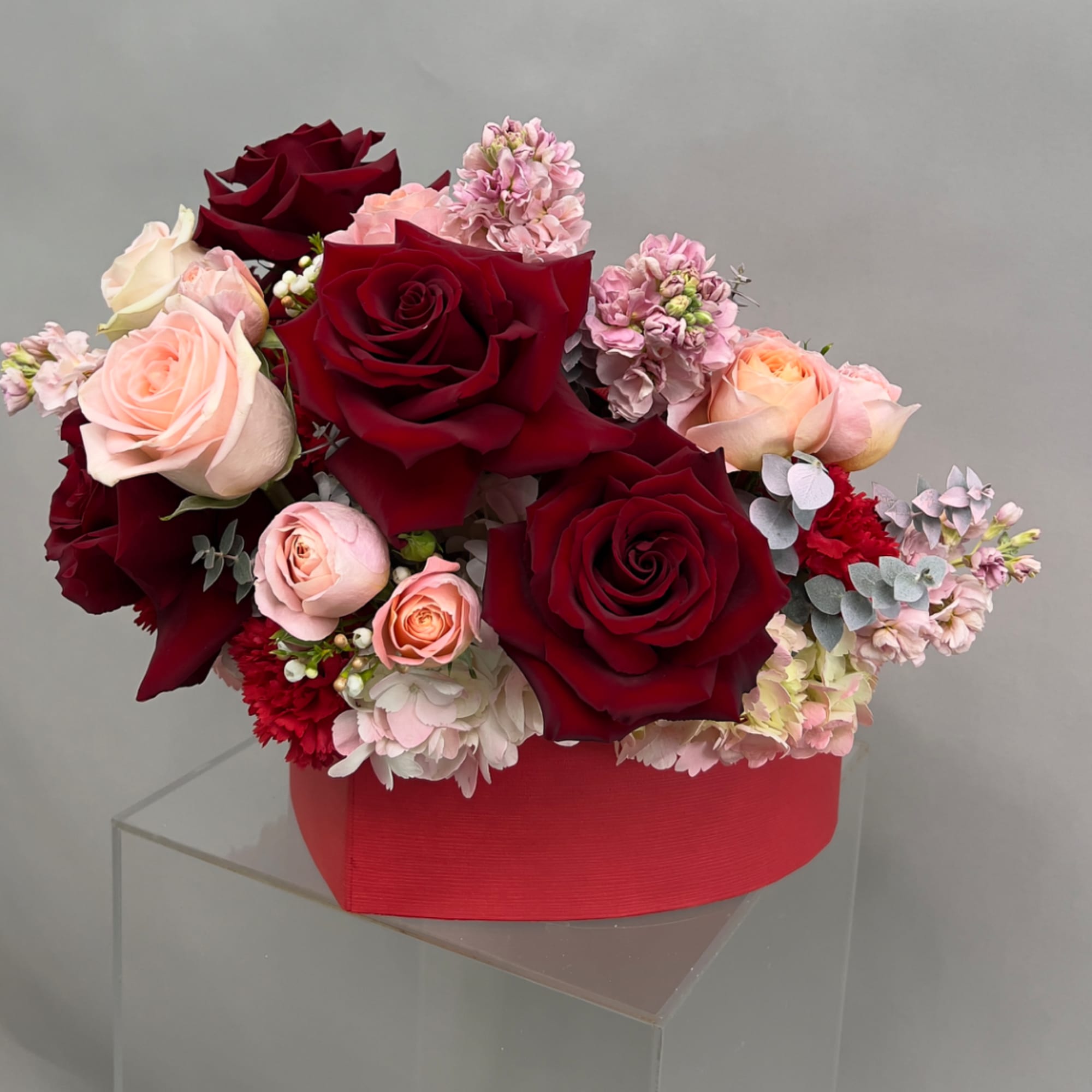 Red and blush rose arrangement in a red box