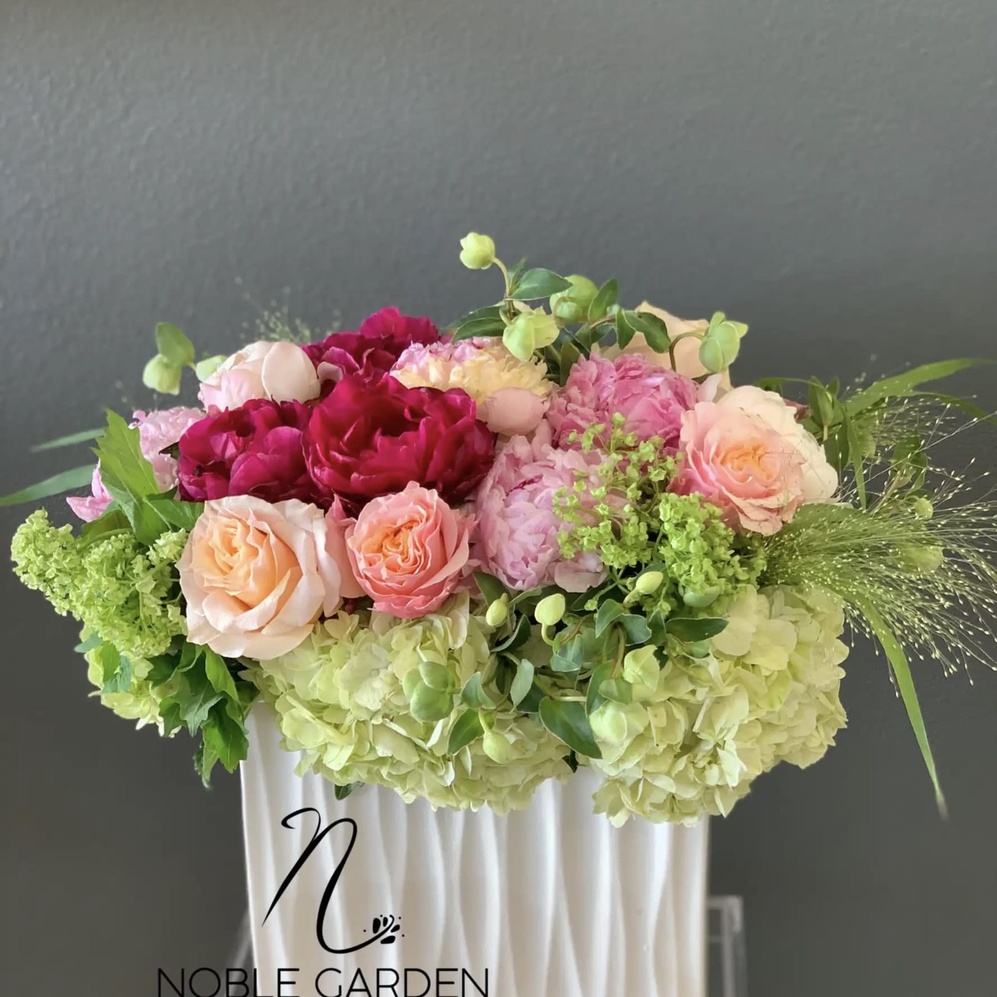 Mixed pink and peach roses with hydrangeas in a white vase