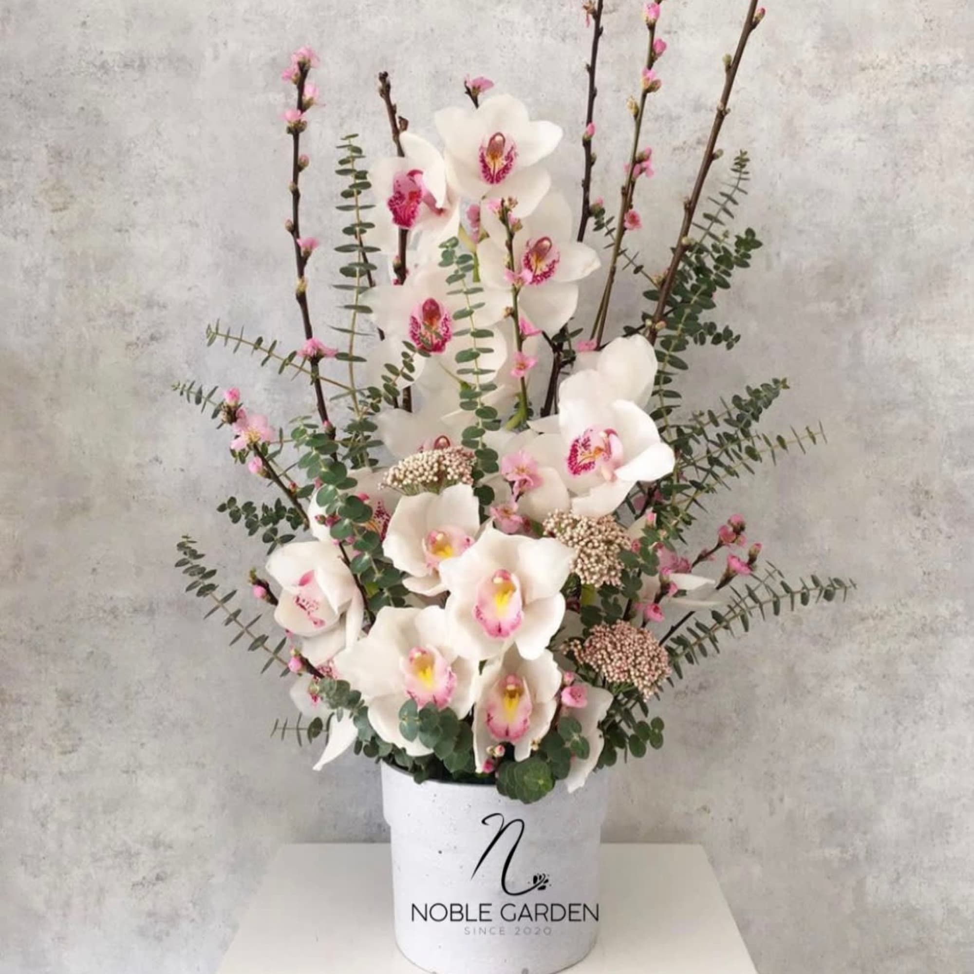 White orchids arranged in a white container with pink accents