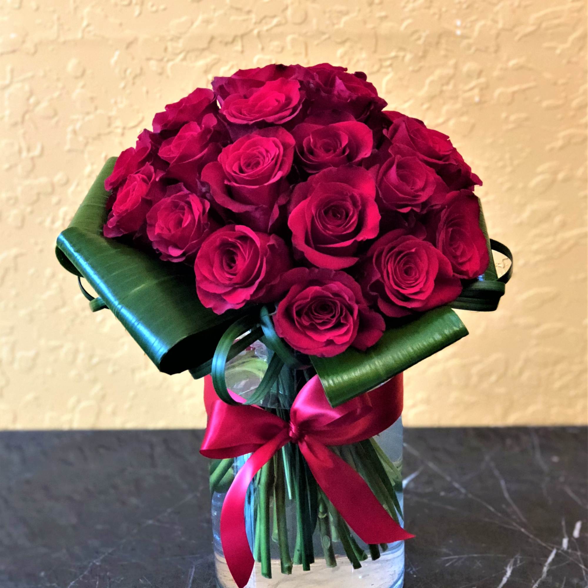 Bouquet of deep pink roses wrapped in green paper with a pink ribbon