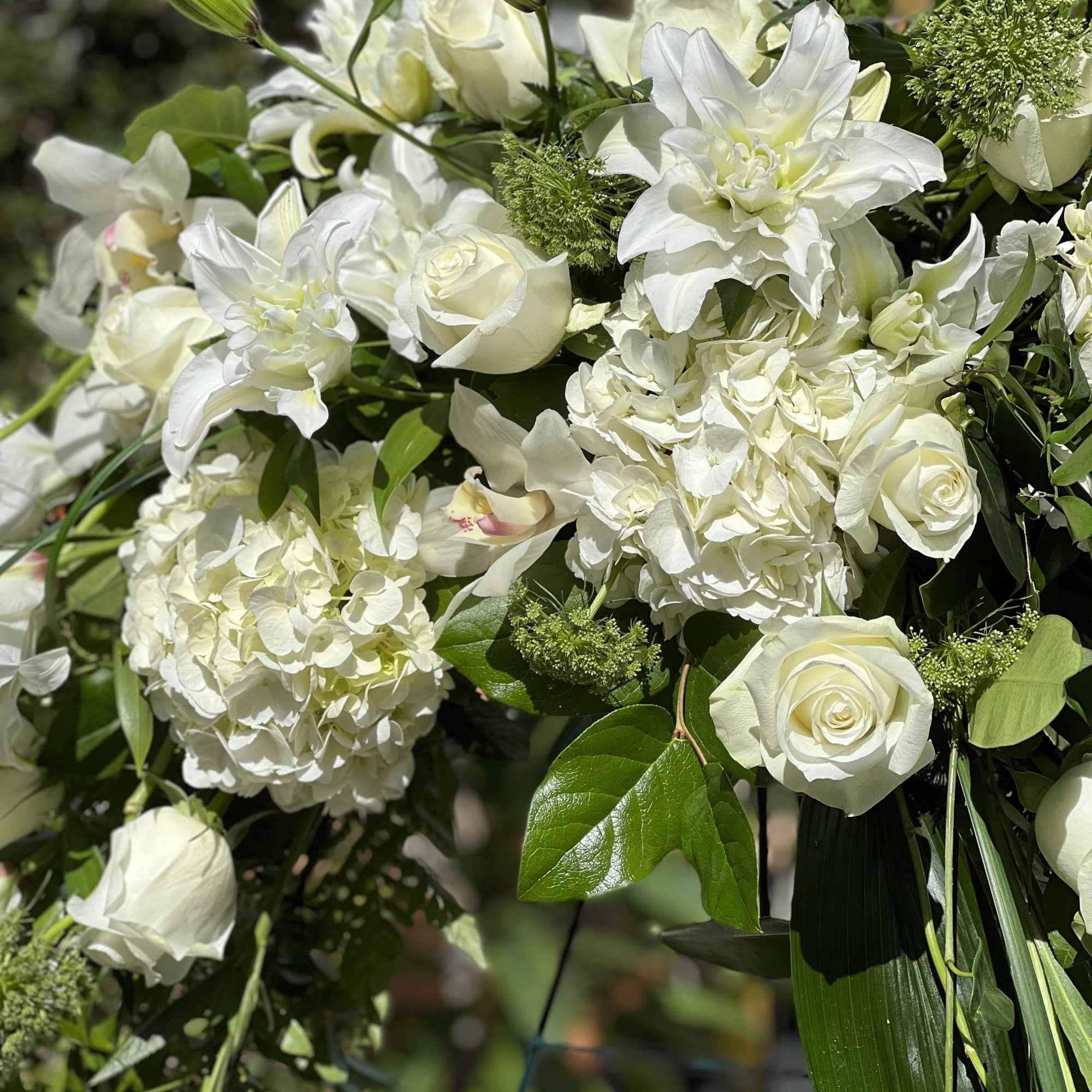 White floral arrangement with roses, hydrangeas, lilies, and orchids