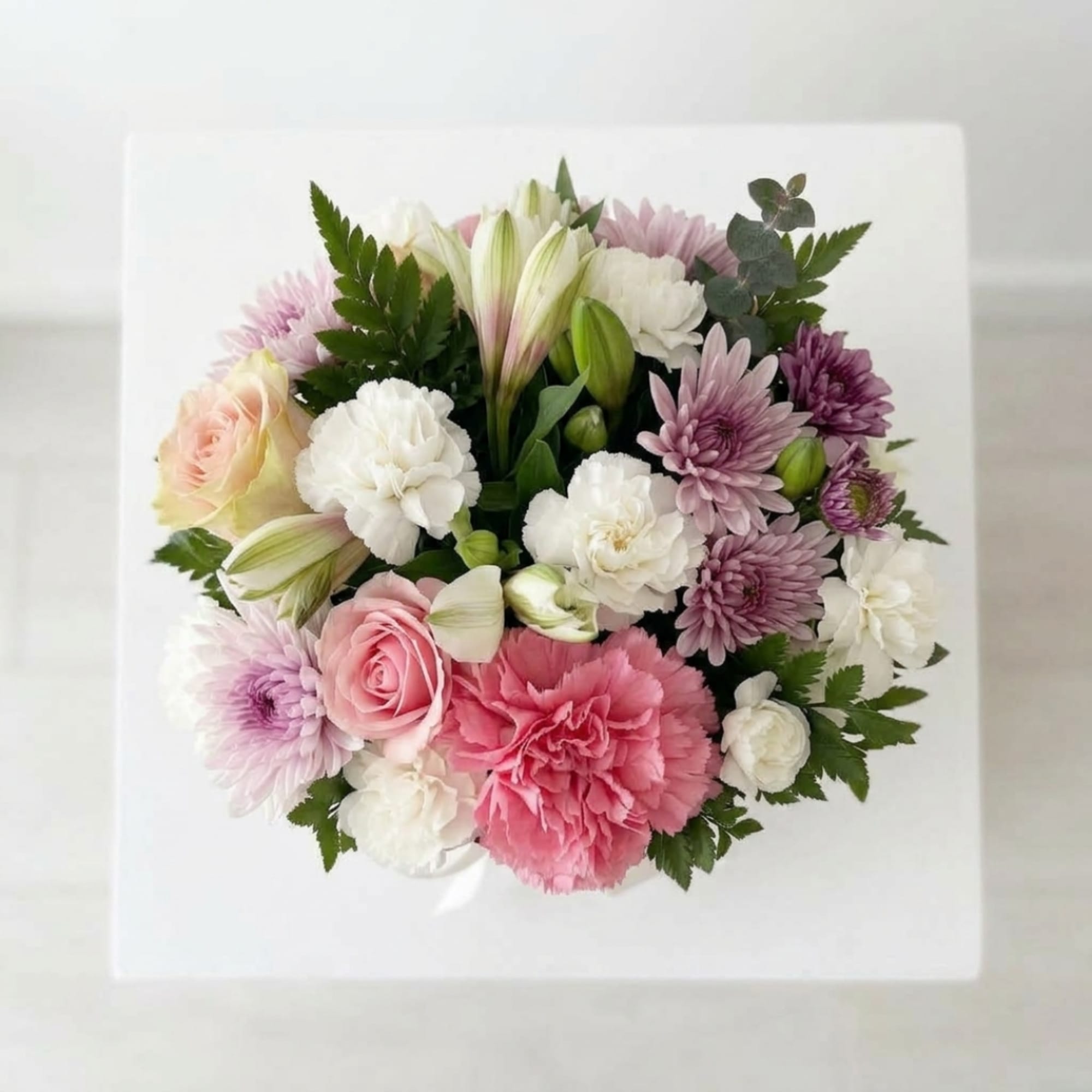 Mixed pink, white, and lavender bouquet in a white square box