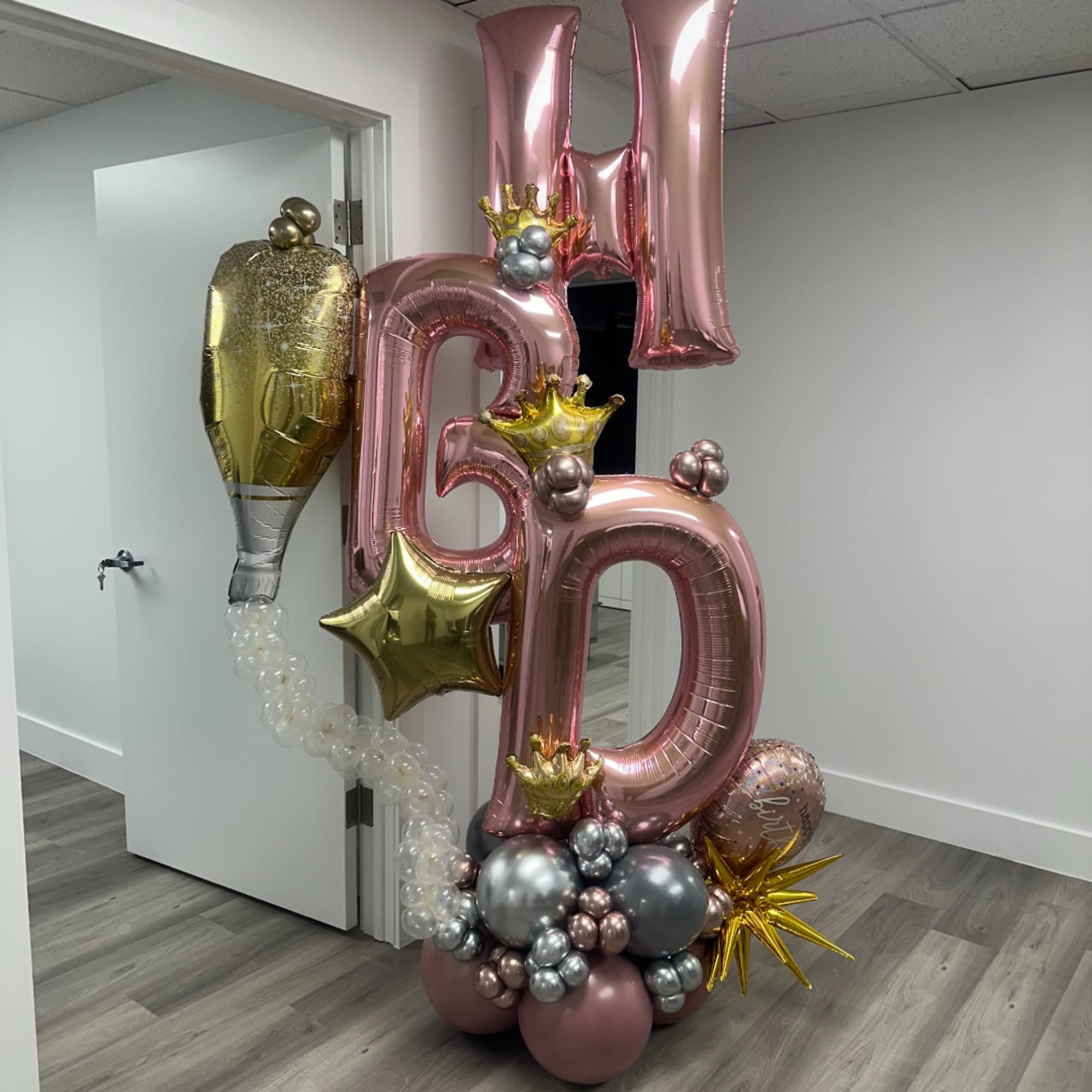 Pink and gold birthday balloon display with large number balloons and star accents