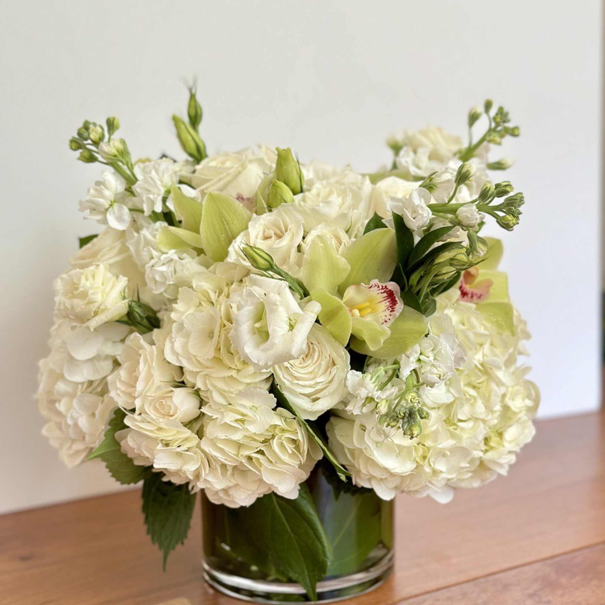 Cream and white bouquet in a clear glass vase with pale green accents