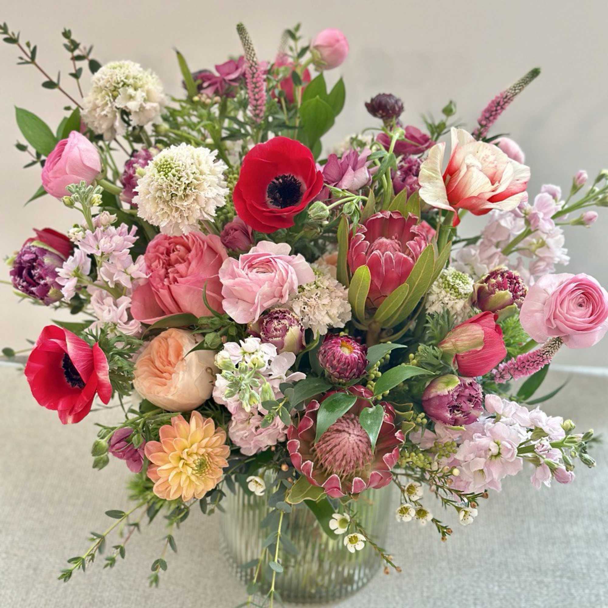 Mixed bouquet of pink, red, and white flowers in a glass vase