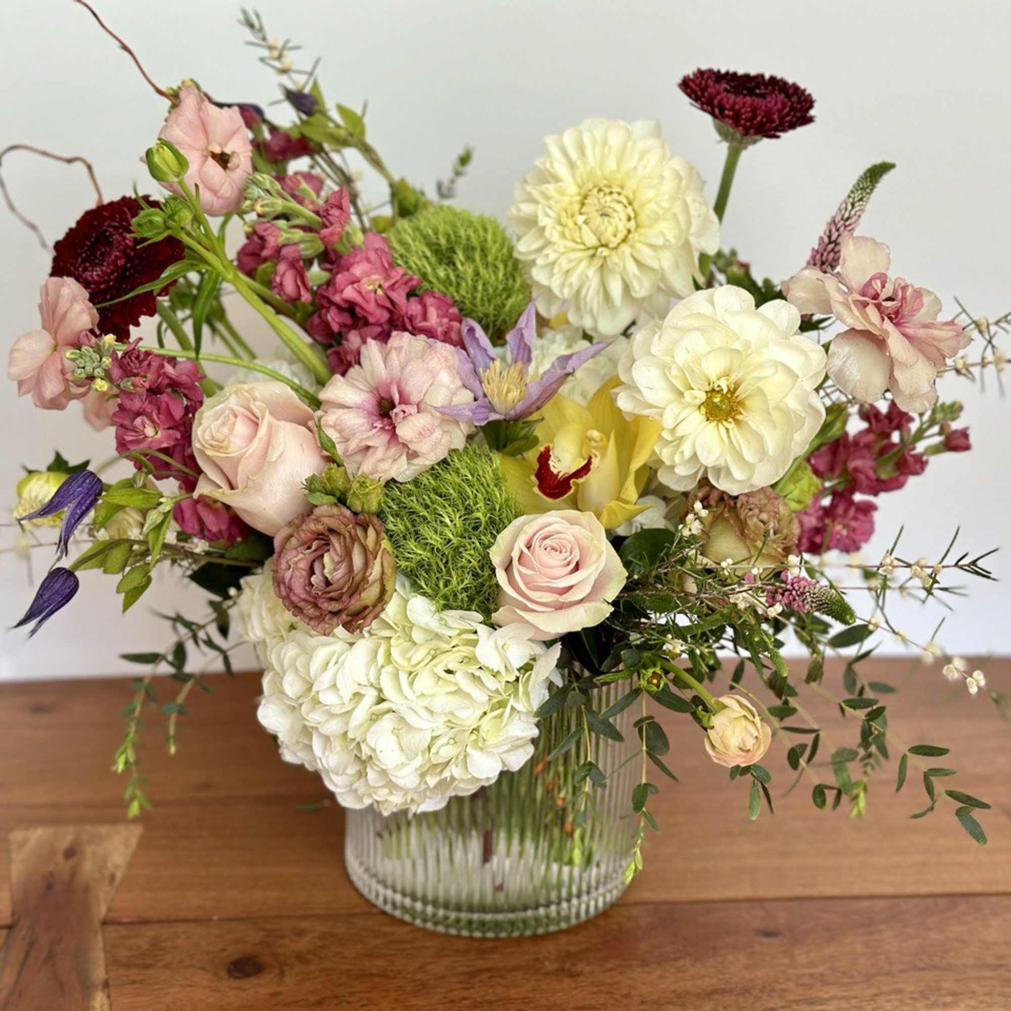 Mixed bouquet of pink, white, and yellow flowers in a glass vase