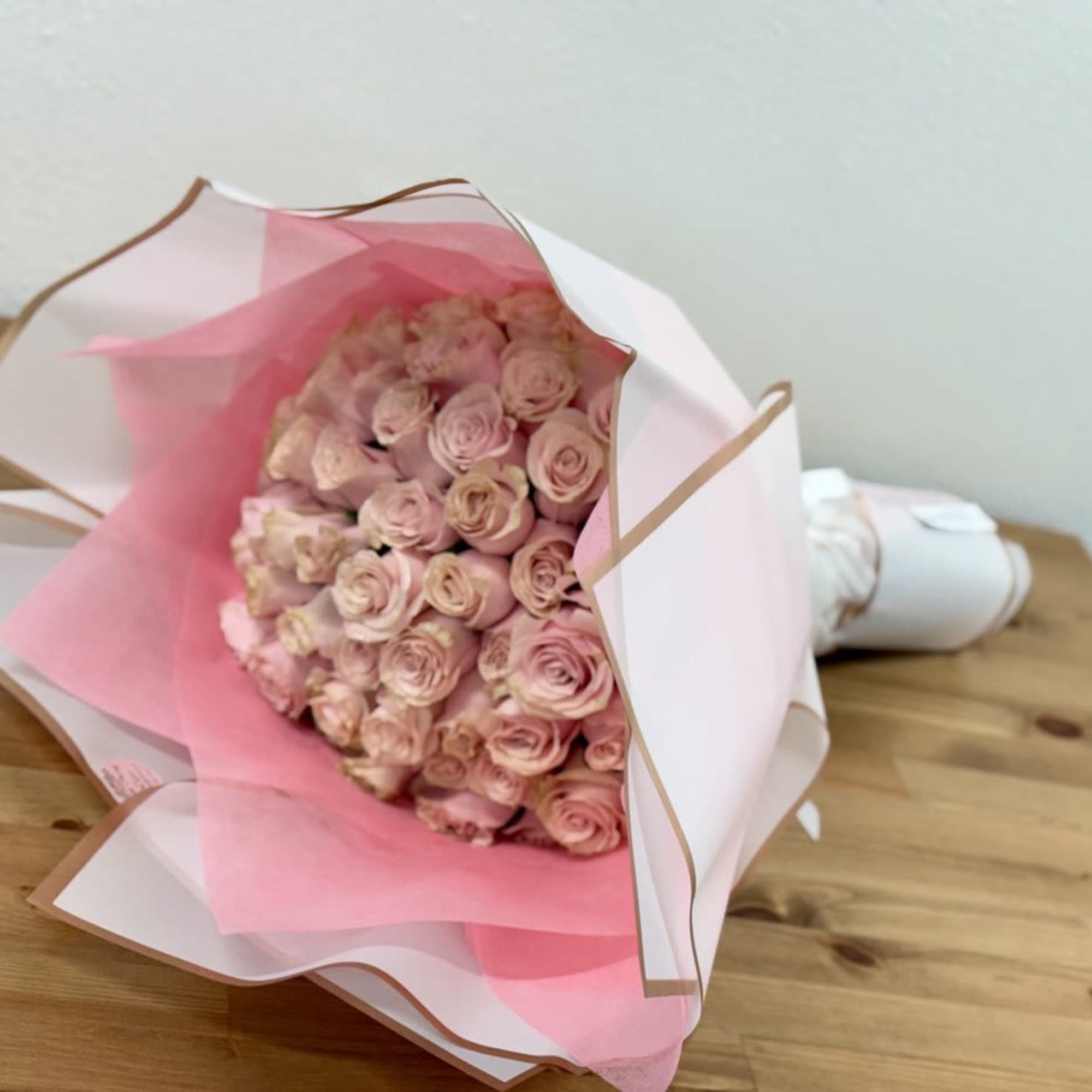 Bouquet of pale pink roses wrapped in white and pink paper