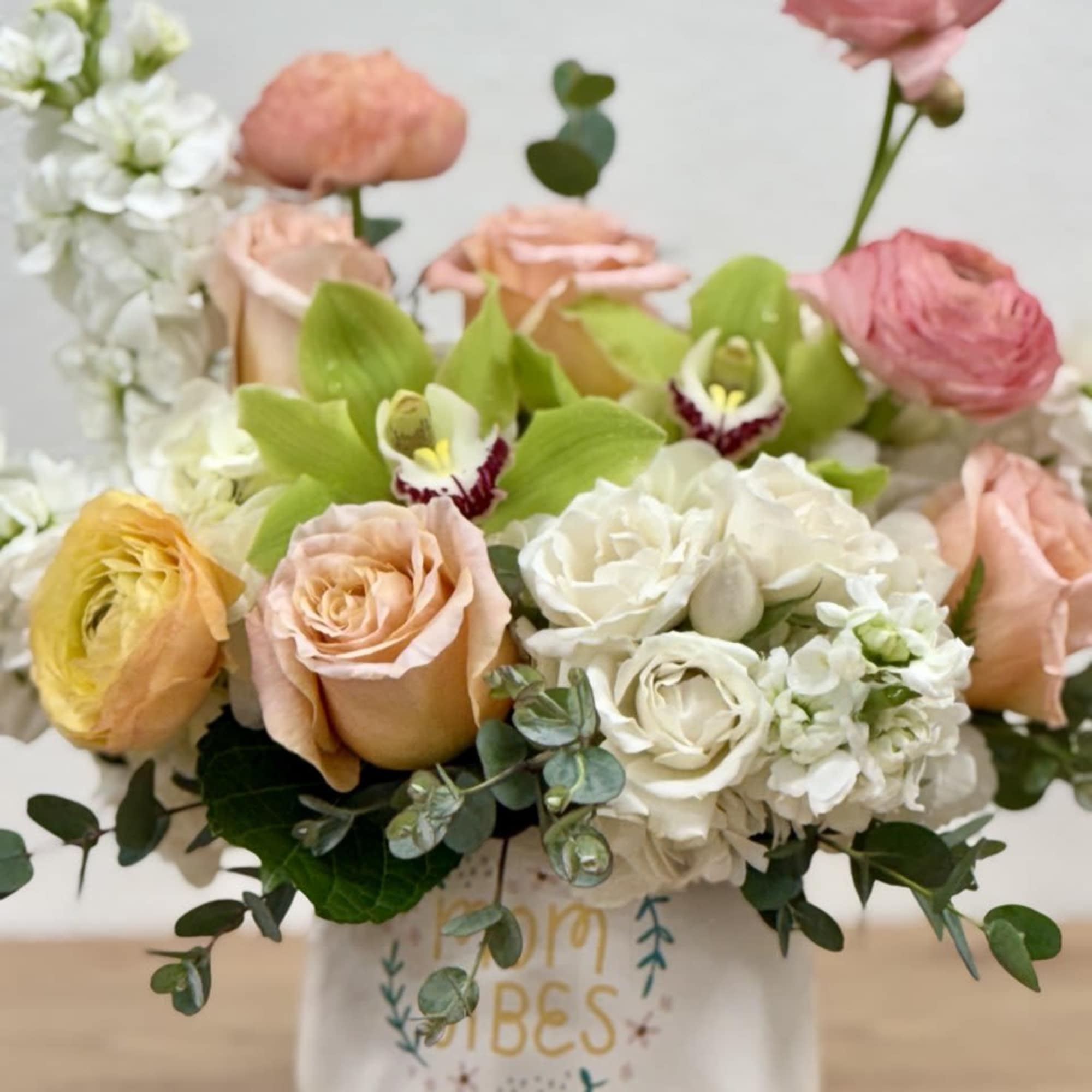 Mixed bouquet of roses, orchids, and white blooms in a ceramic vase