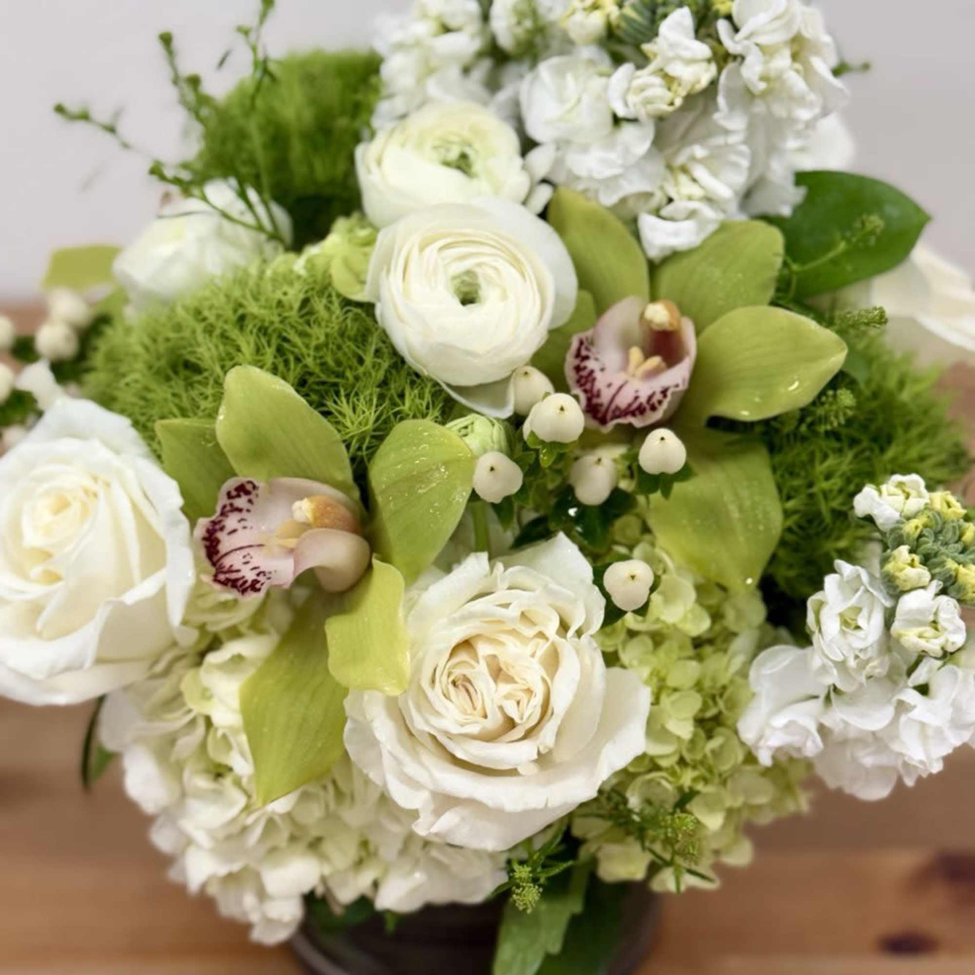 White roses and green orchids arranged in a low vase