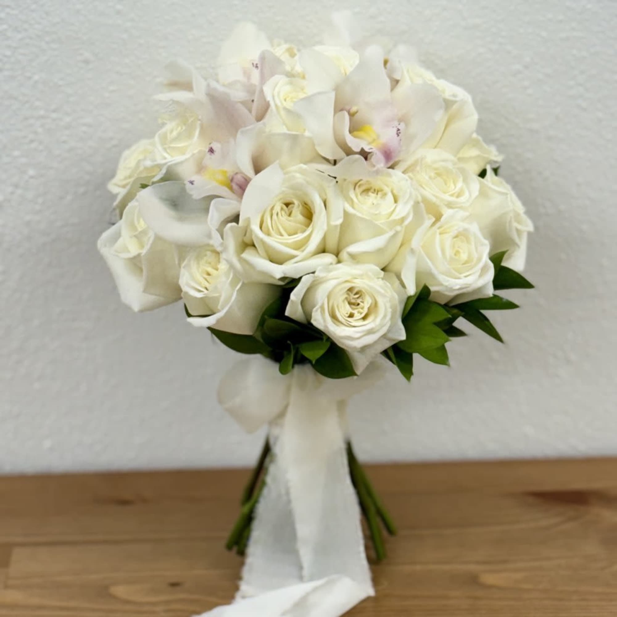 White rose and orchid bouquet with a white ribbon wrap