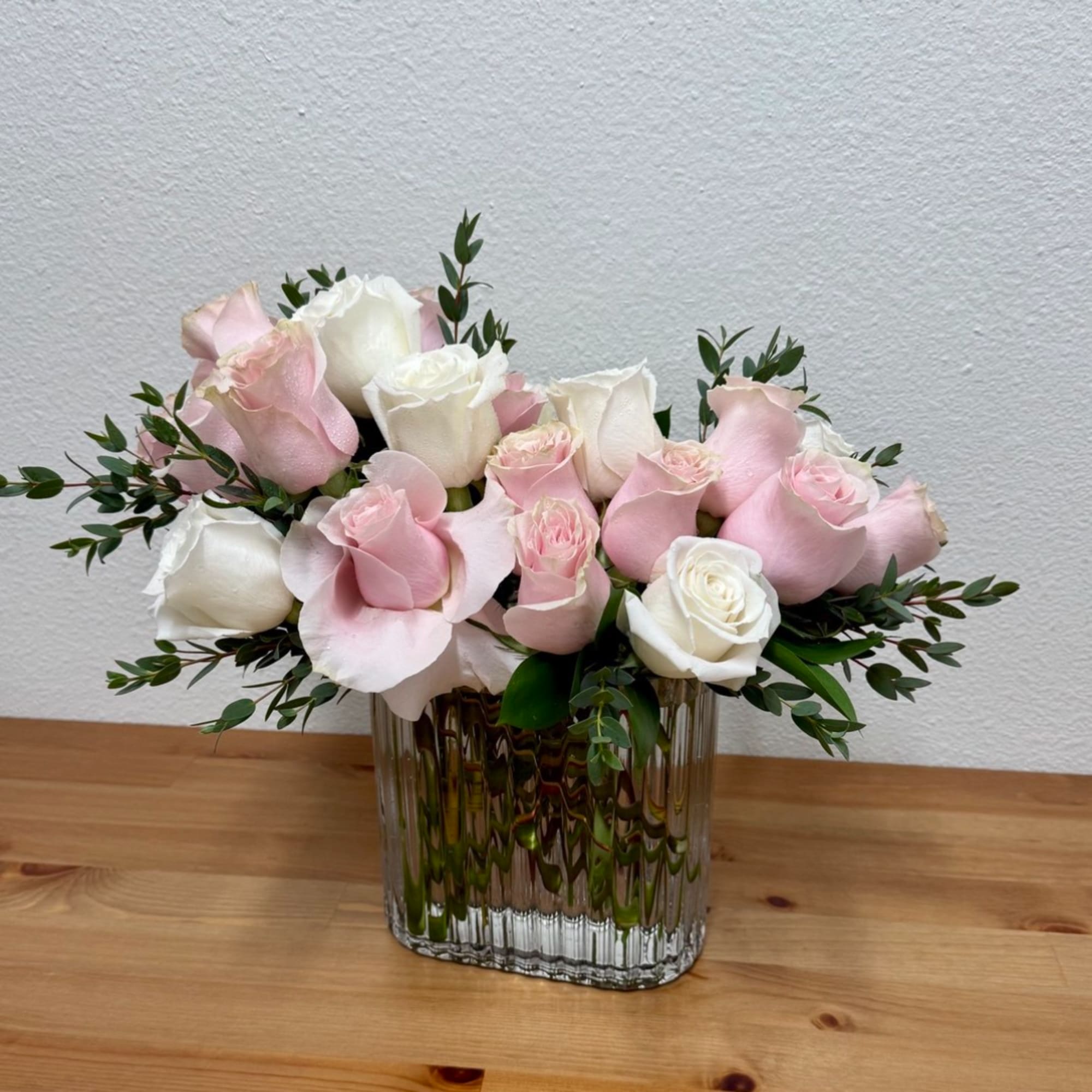 Pink and white roses arranged in a clear glass vase, photo 2 of 3