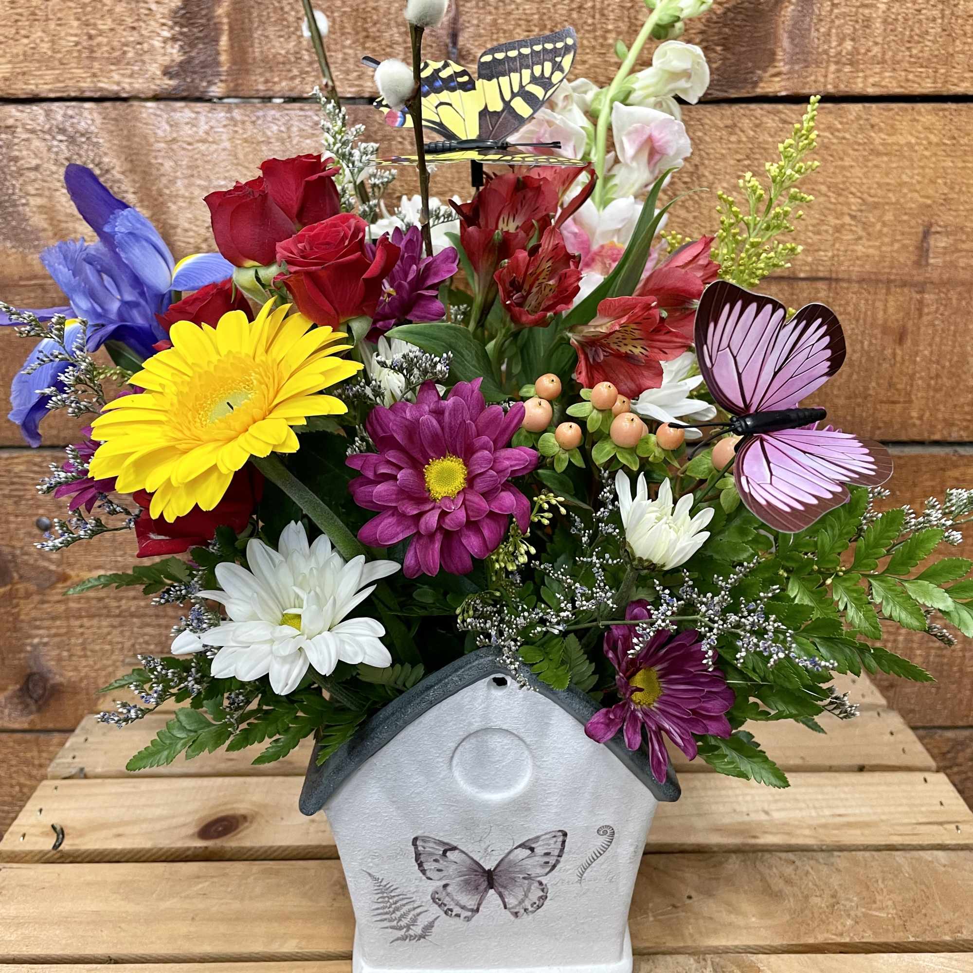 Colorful flower arrangement in a butterfly-decorated house-shaped container
