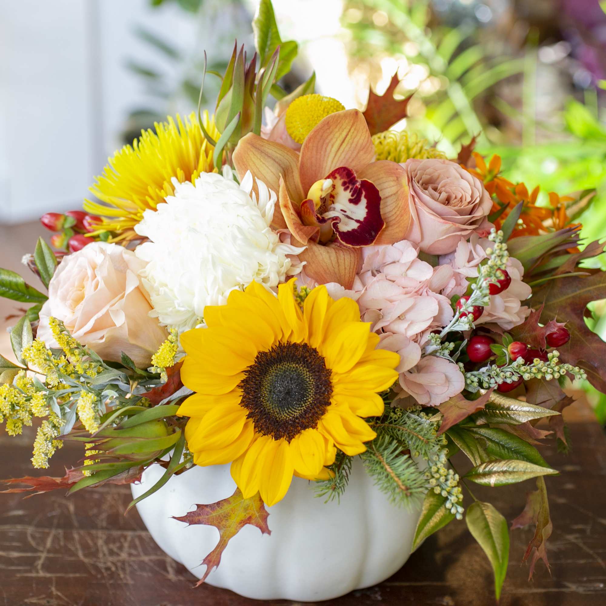 White ceramic pumpkin filled with seasonal blooms and accents