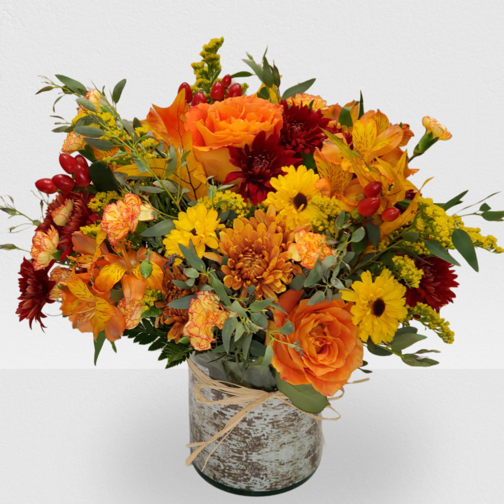 Orange and yellow mixed bouquet in a rustic vase with a twine bow