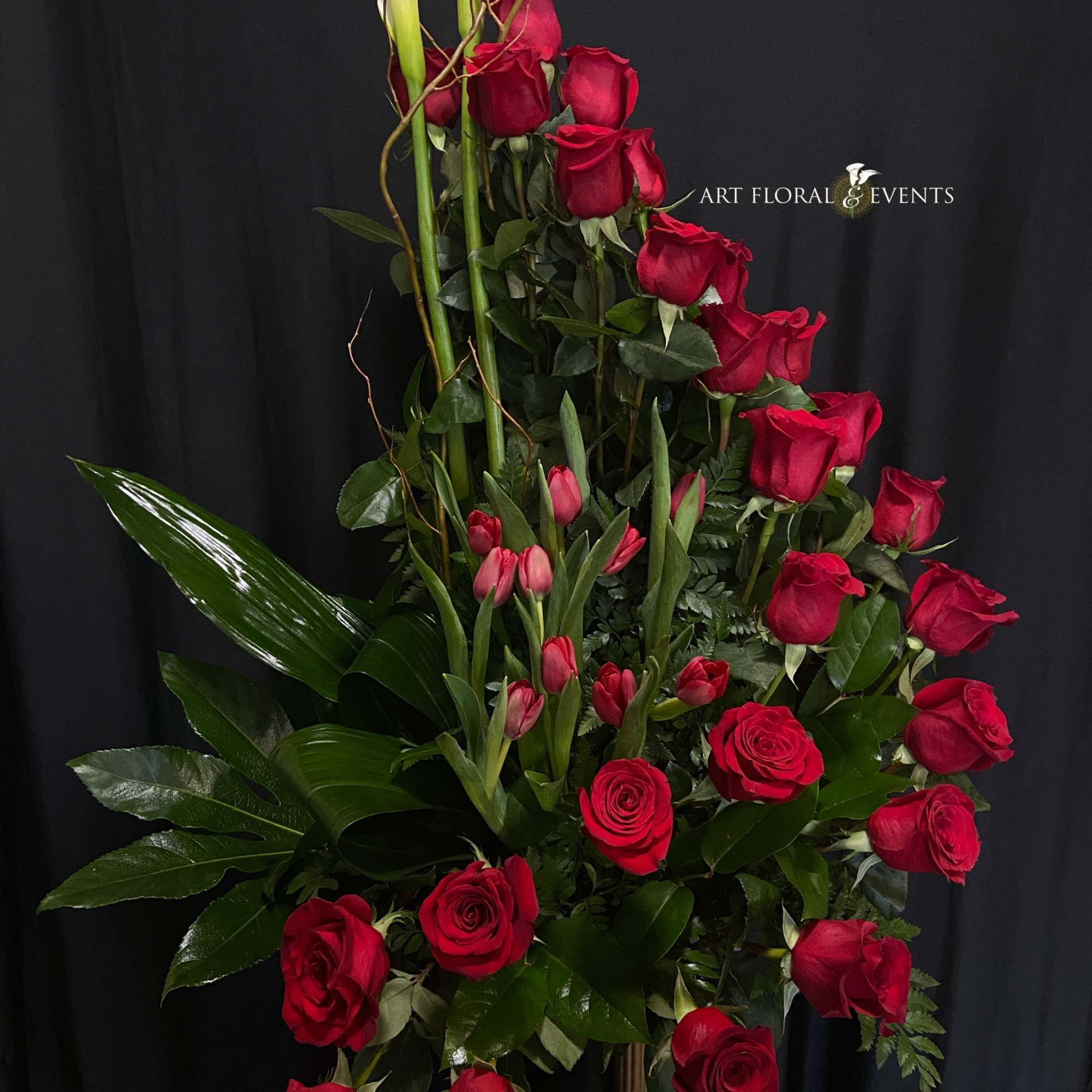 Tall arrangement of red roses and pink tulips with white calla lilies